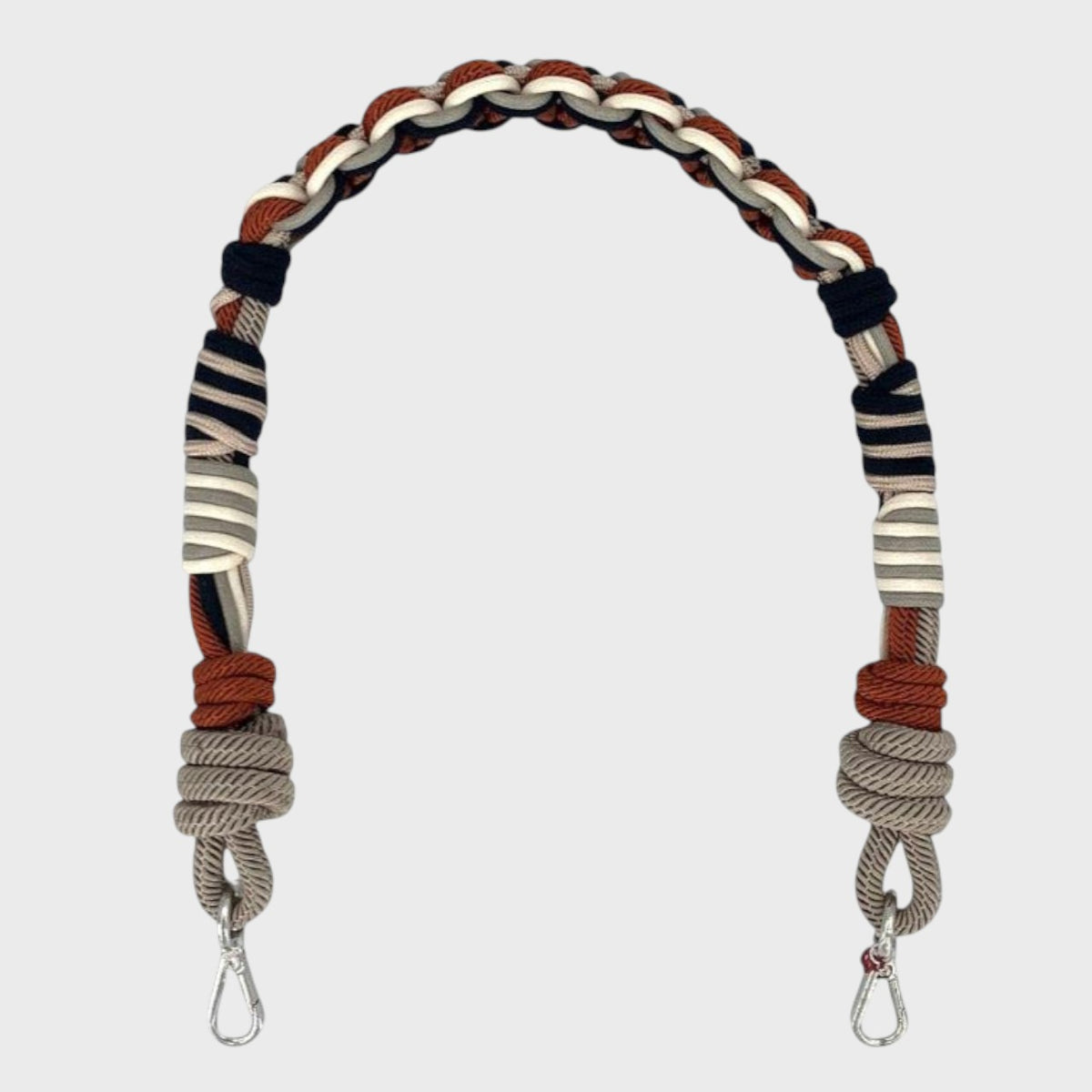 Braided macramé bag strap with grey, white, black and red accents on a light gray background