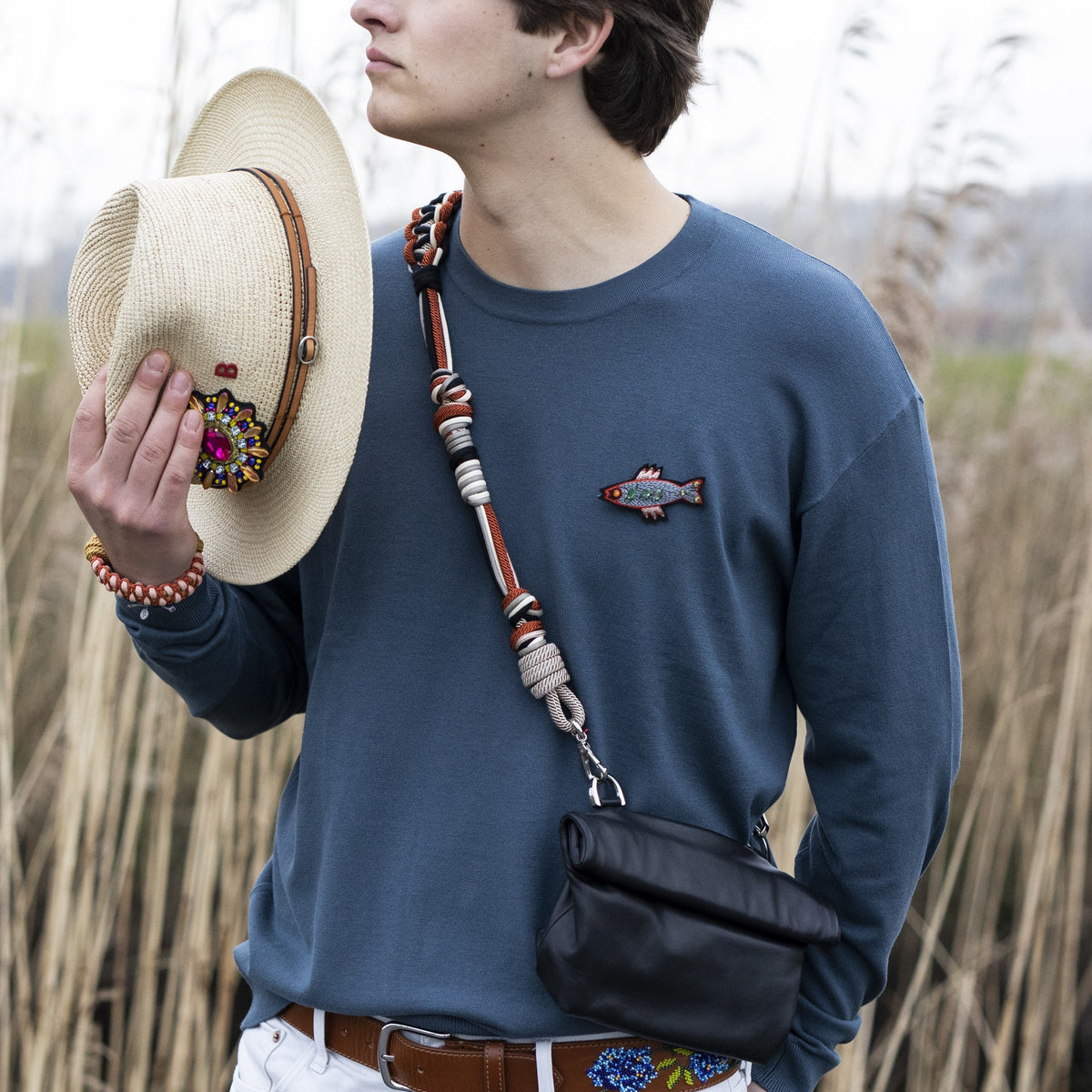 A person wearing features a colorful macramé strap across the body with a small black bag attached to it.
