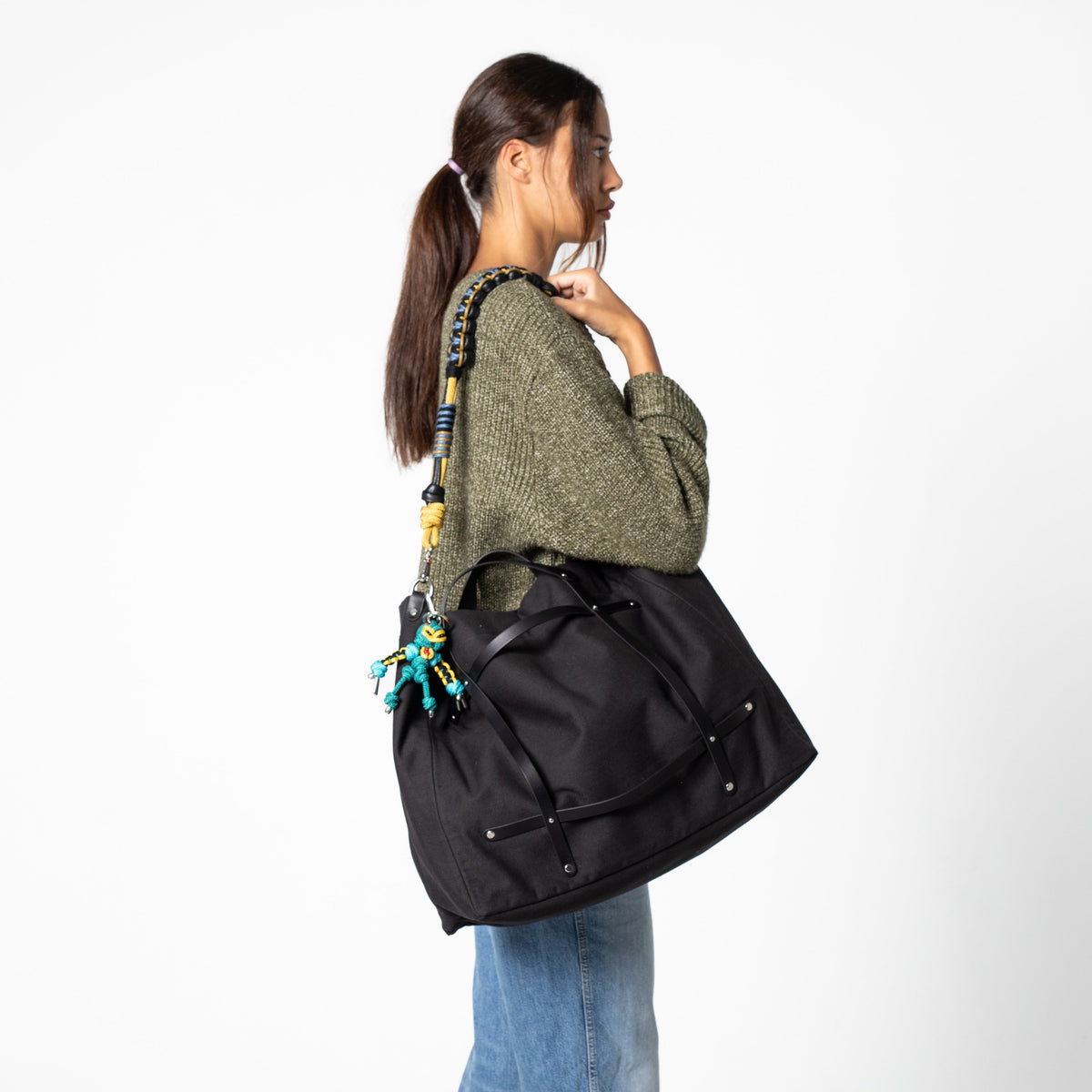 Woman carrying a black bag with a bag strap on a white background