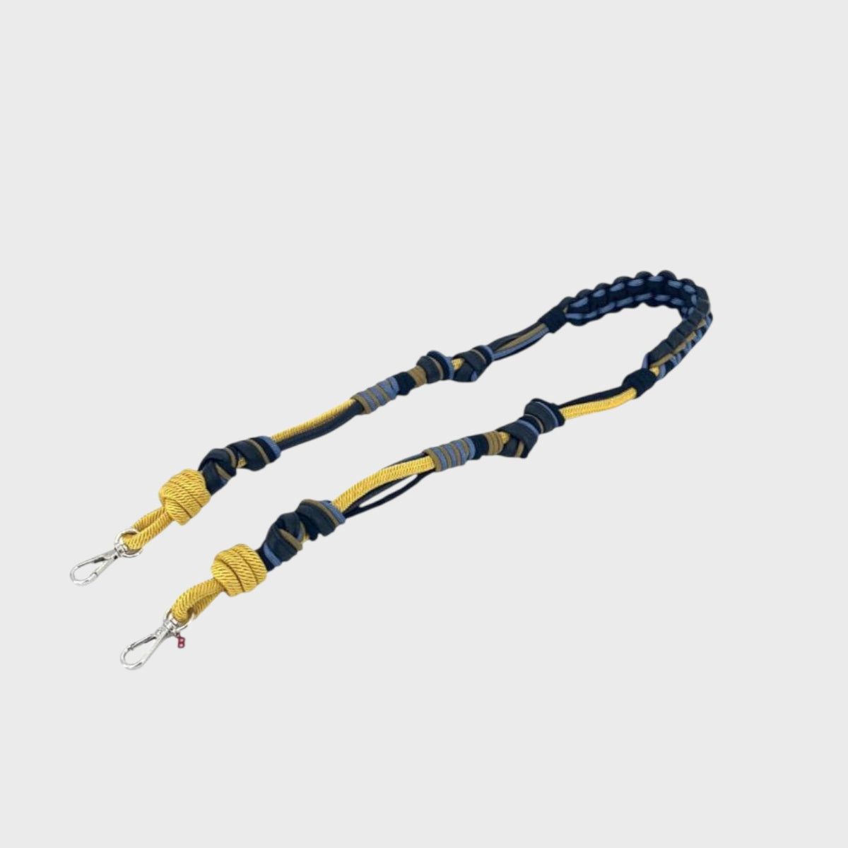 A long bag strap with black leather and yellow and blue macramé.