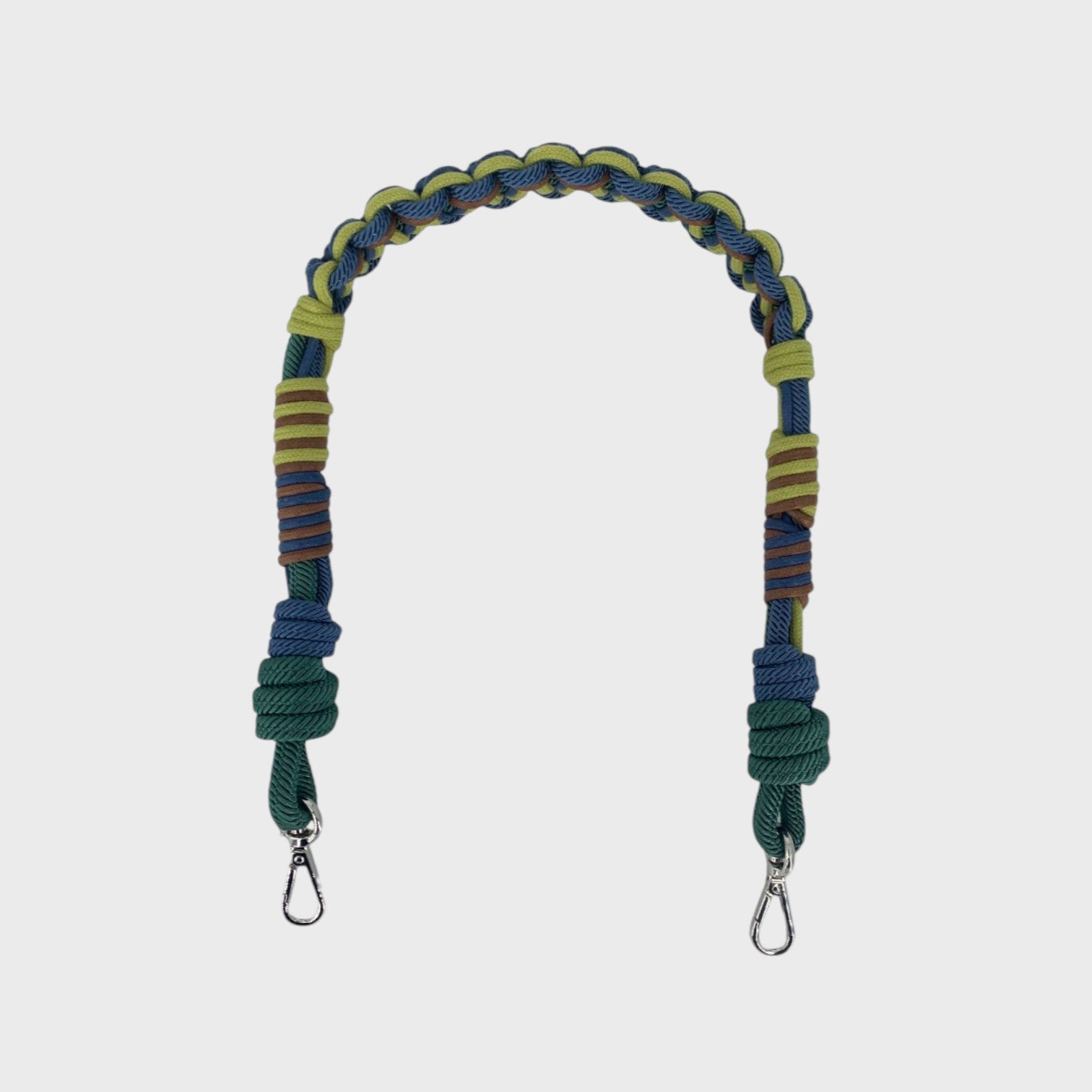 Multicolored braided macramé bag strap in bright and dark green, dark blue, and brown, shown on a light gray background.