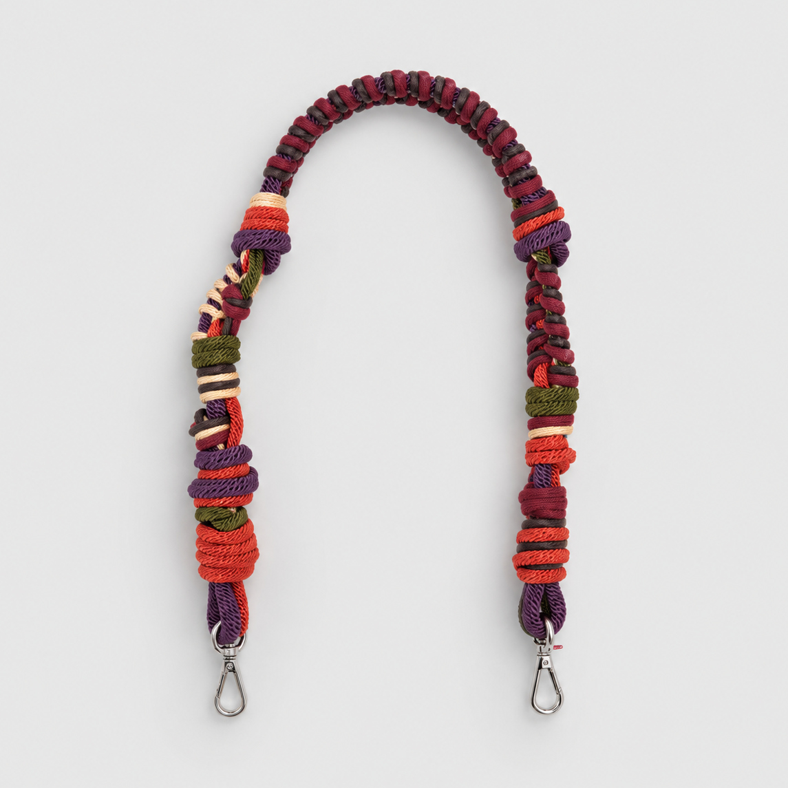 Multicolored braided macramé bag strap in dark green, purple, and orange, shown on a light gray background.