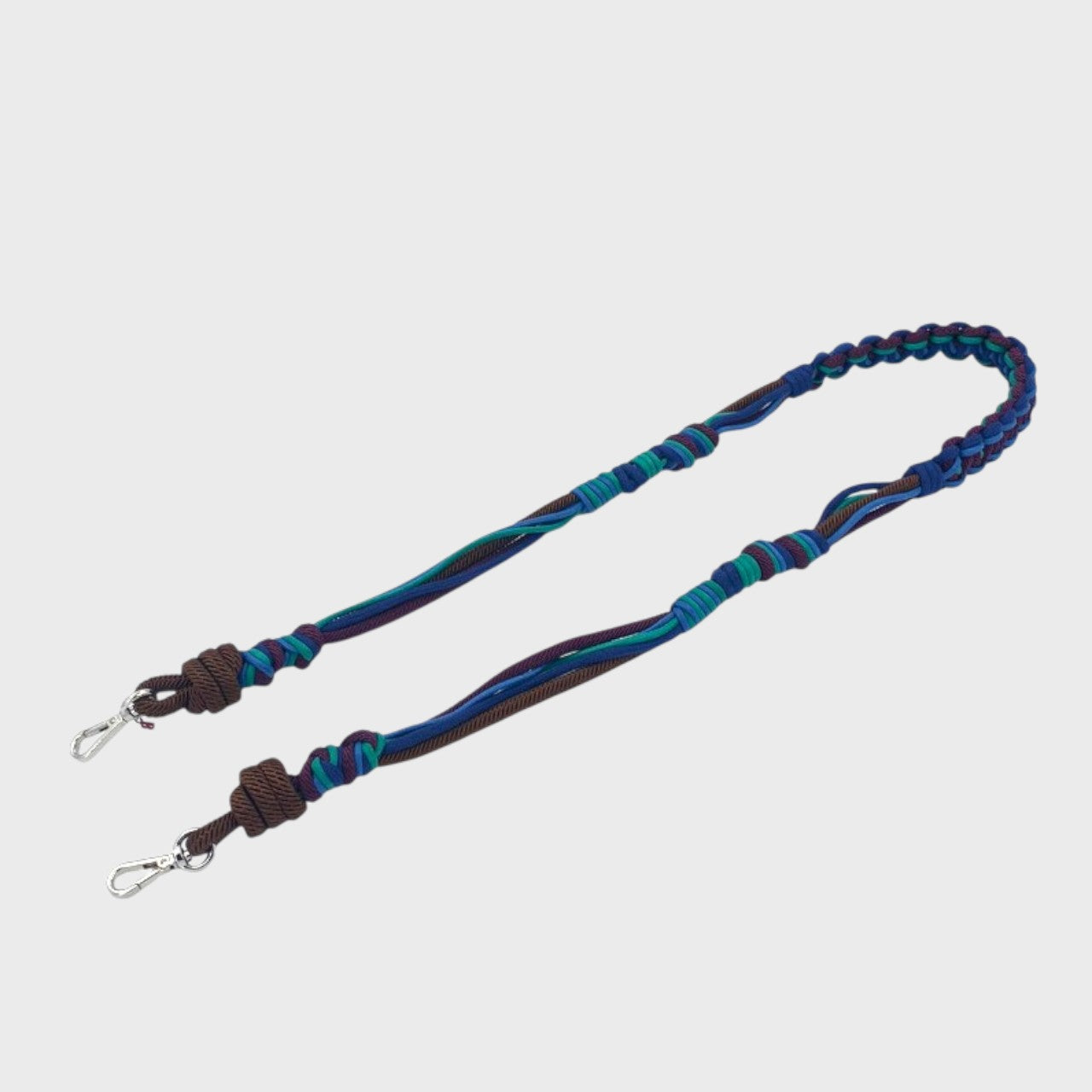 Multicolored braided macramé bag strap in various blues, with accents of purple and brown shown on a light gray background.