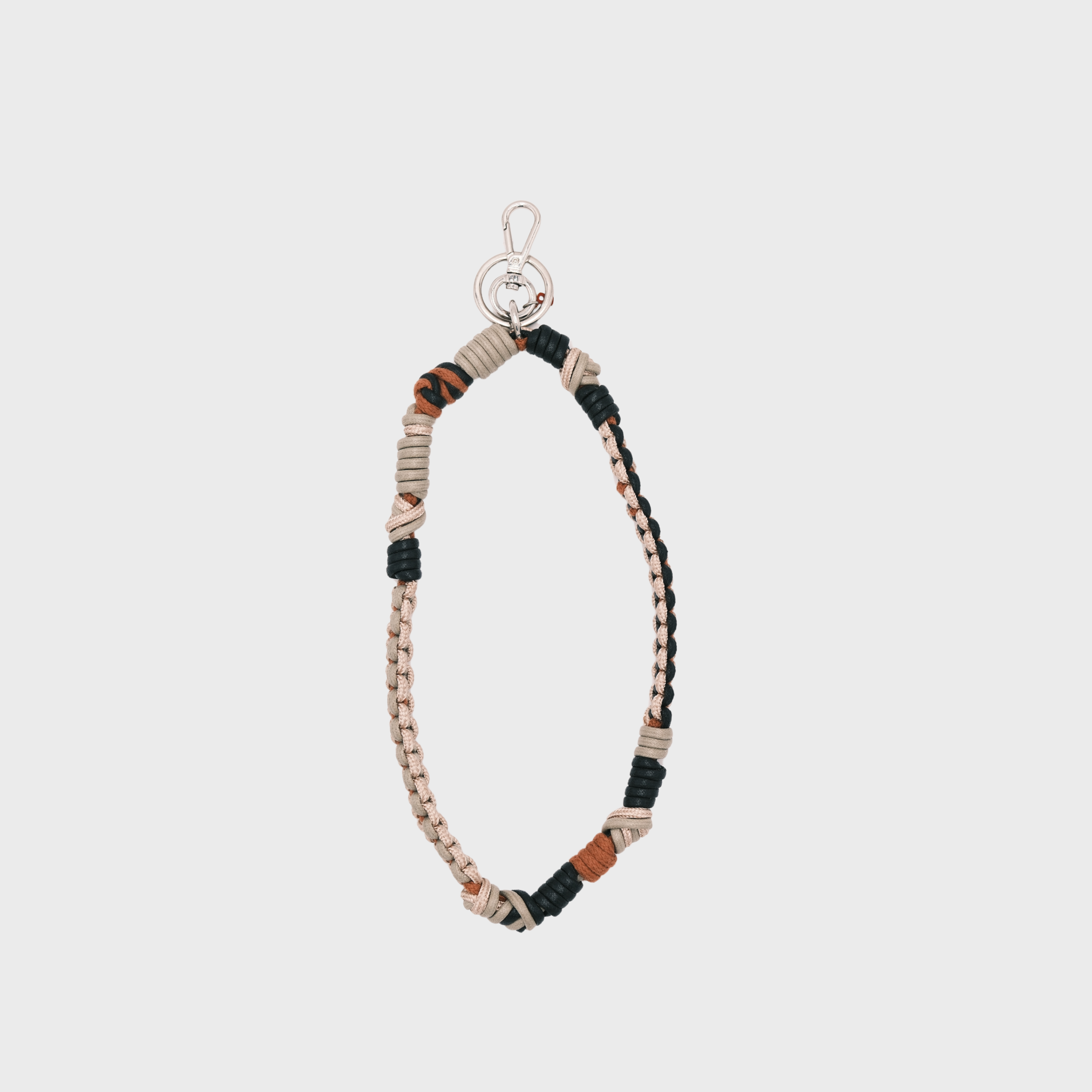 A bohemian-style woven macramé key chain with a silver-tone lobster clasp, featuring beige, black, and terracotta brown woven segments on a light gray background.
