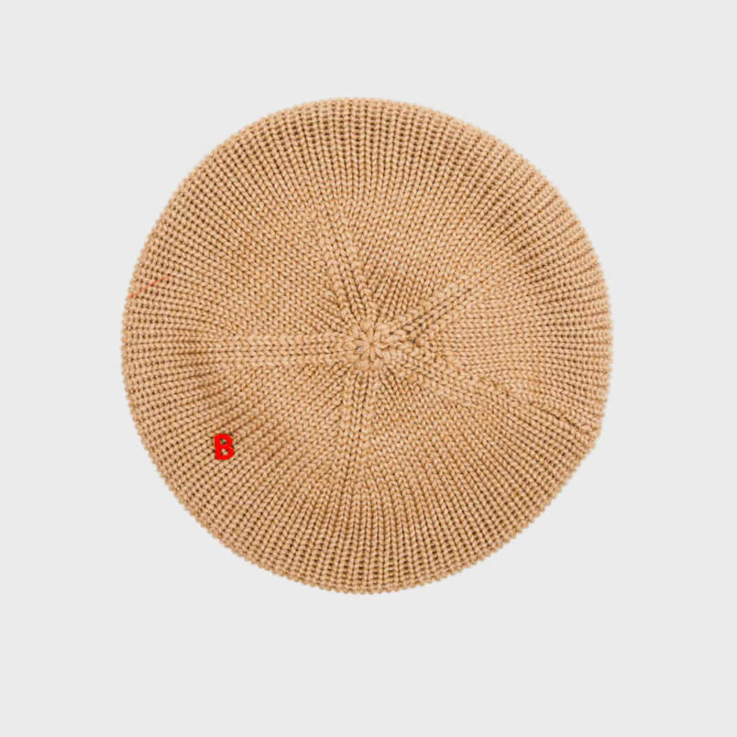 Beige knitted beret on a light gray background