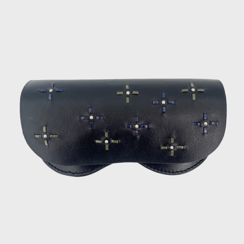Black eyeglasses case with embroidered studs on a light gray background.