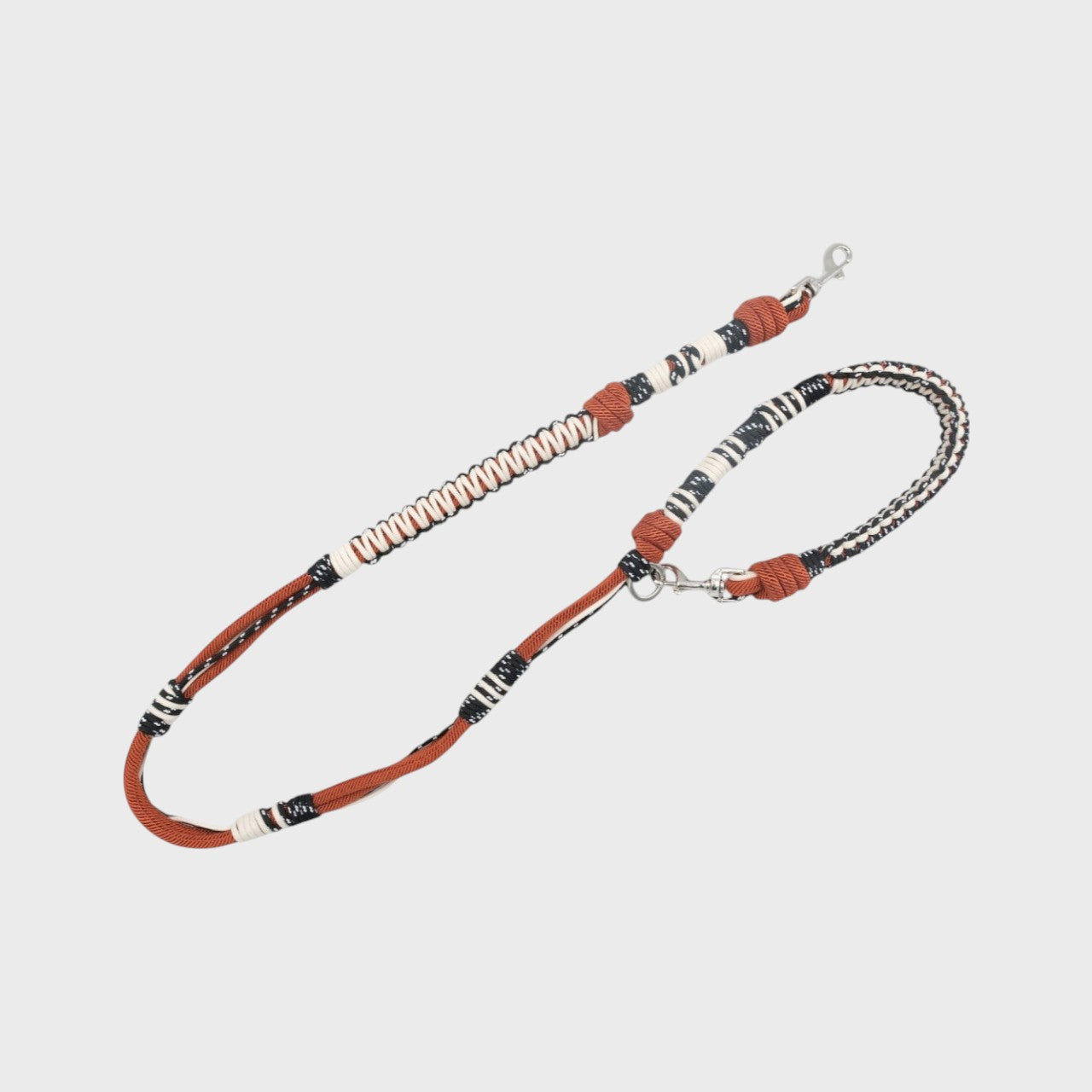A braided macramé dog leash with black, white and dark red woven sections, and a silver metal hardware