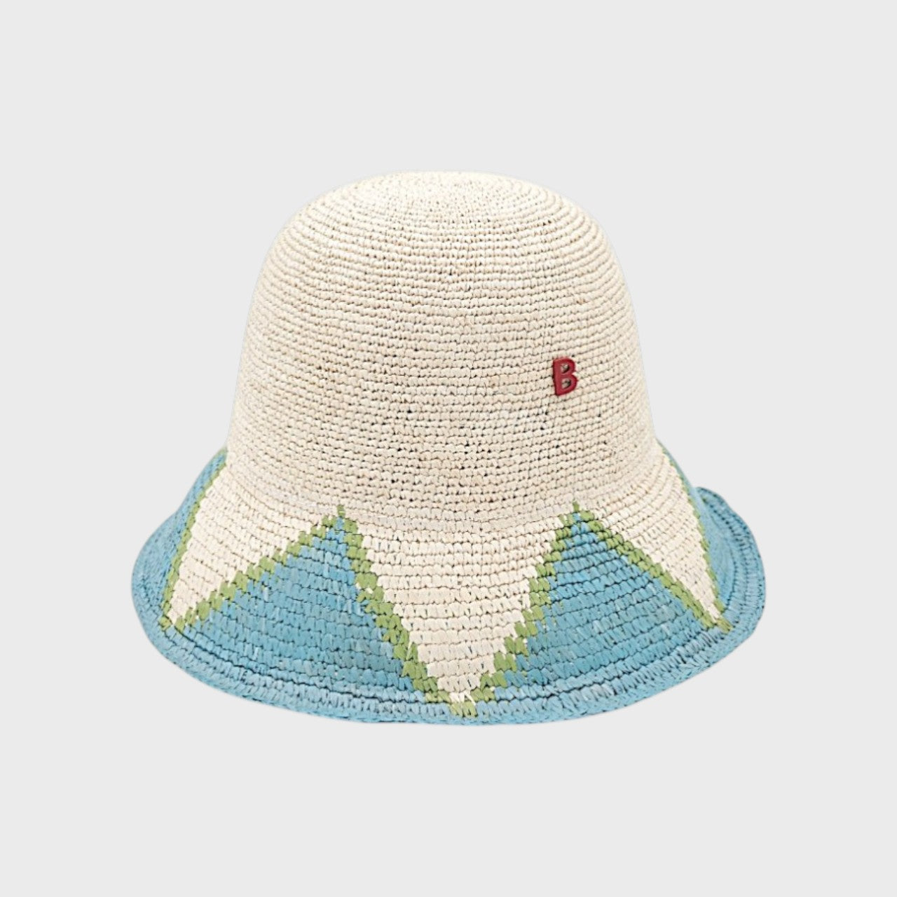 Two-toned raffia bucket hat with blue, green and beige accents on a light gray background