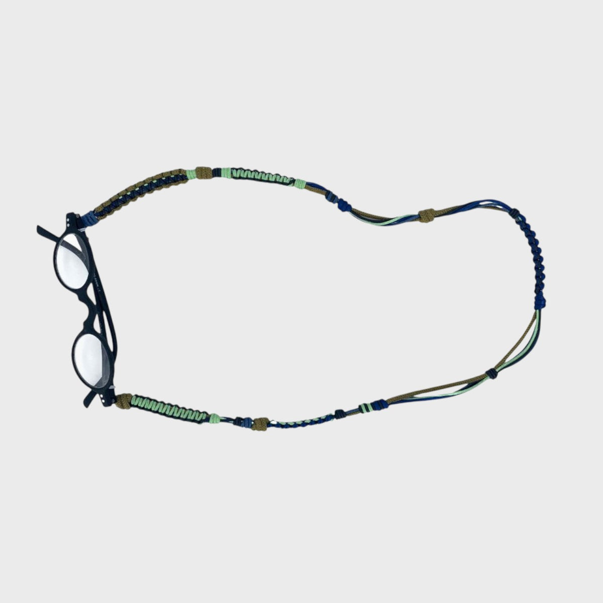 Glasses with a colorful macramé wovenned strap on a light gray background