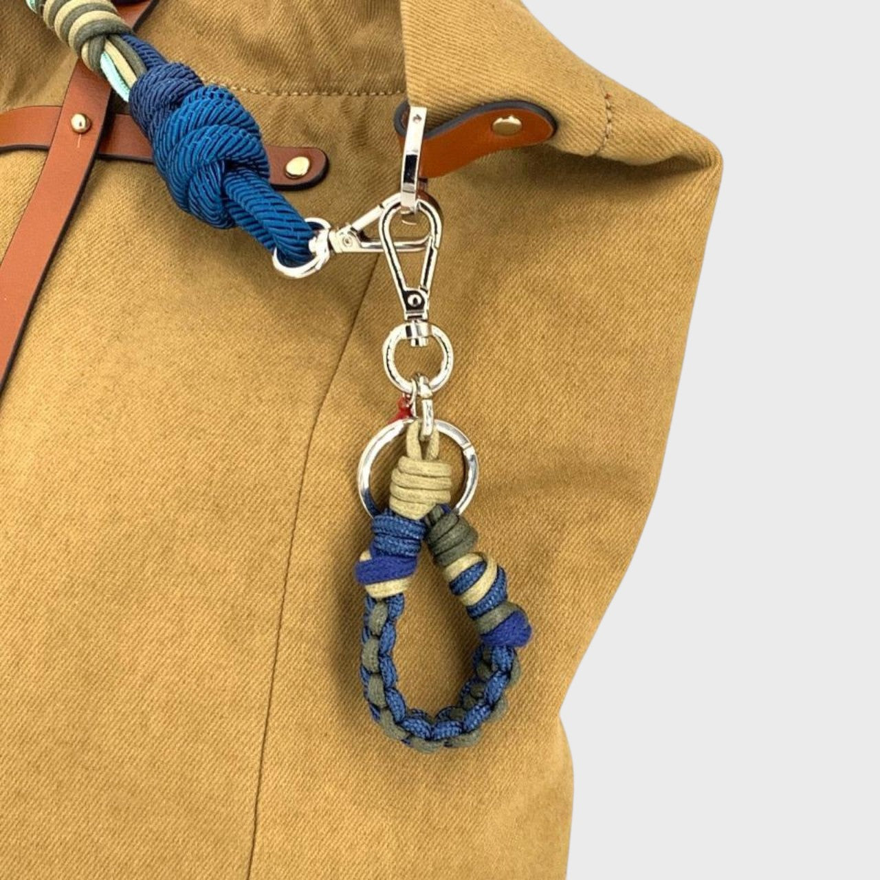 The blue, grey and beige Harold key ring on a mustard bag.