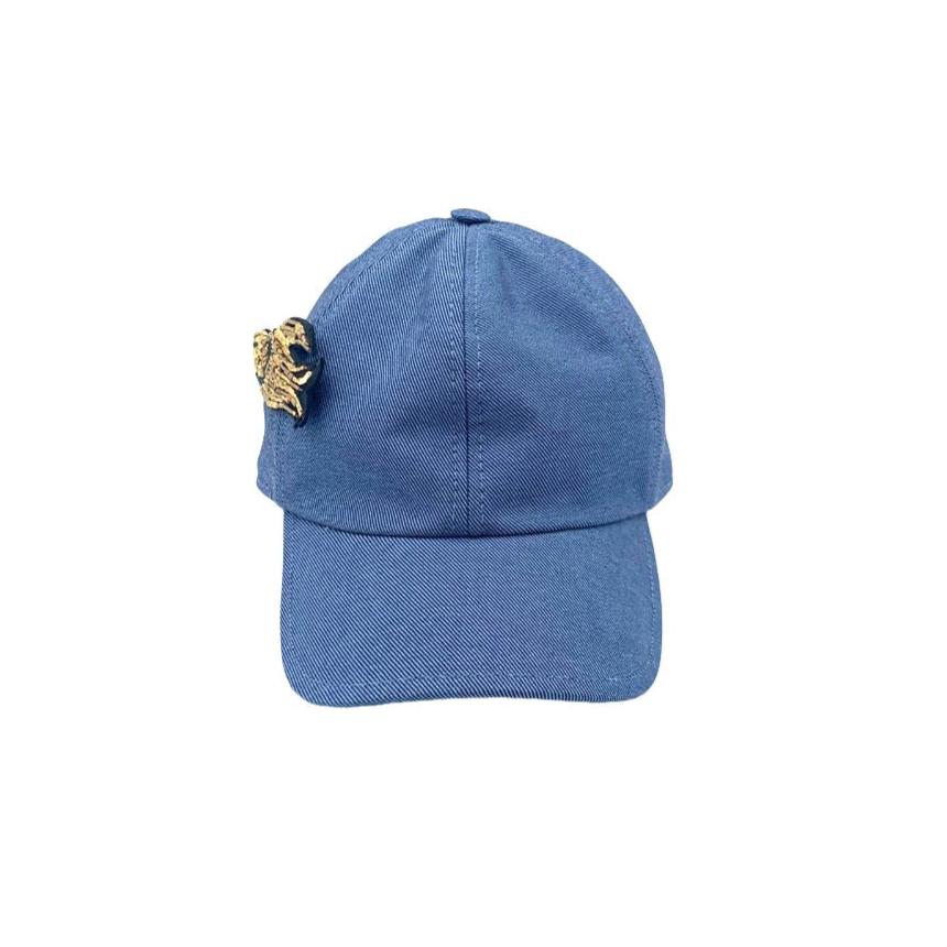 A blue jean cotton cap with a golden embroidered brooch.