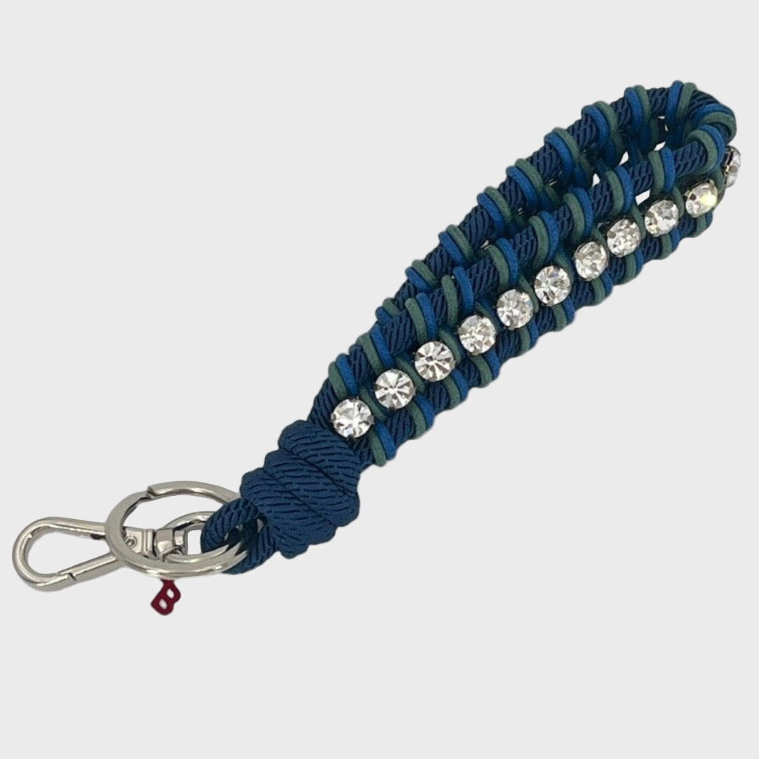 Keychain with dark blue and green patterned band and rhinestones on a white background