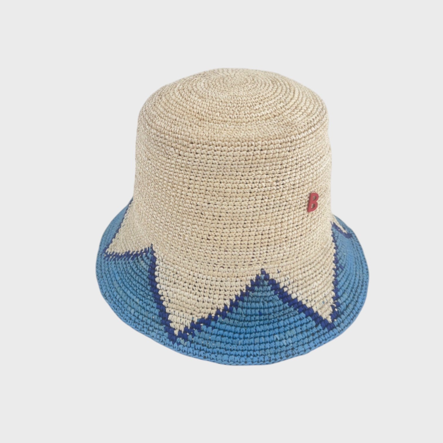 Two-toned raffia bucket hat with blue and beige accents on a light gray background
