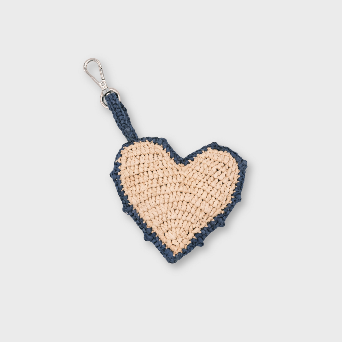 A heart-shaped raffia keychain in beige and navy blue rim, featuring a silver metal clasp.