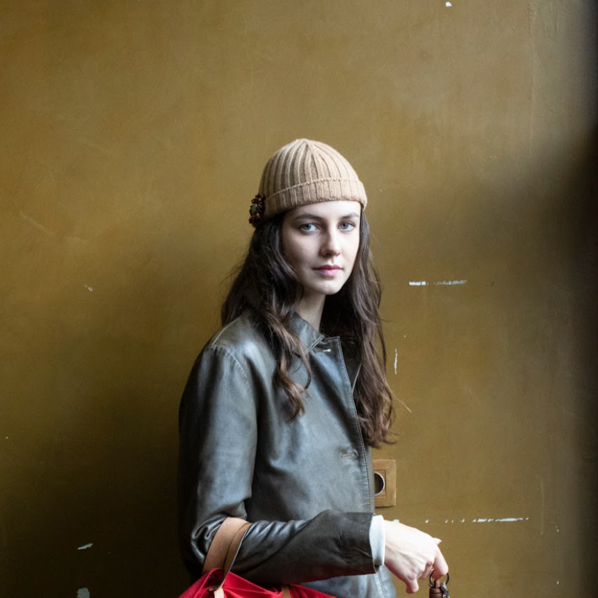 A woman wearing a beige cashmere bonnet with a brooch pinned to it.
