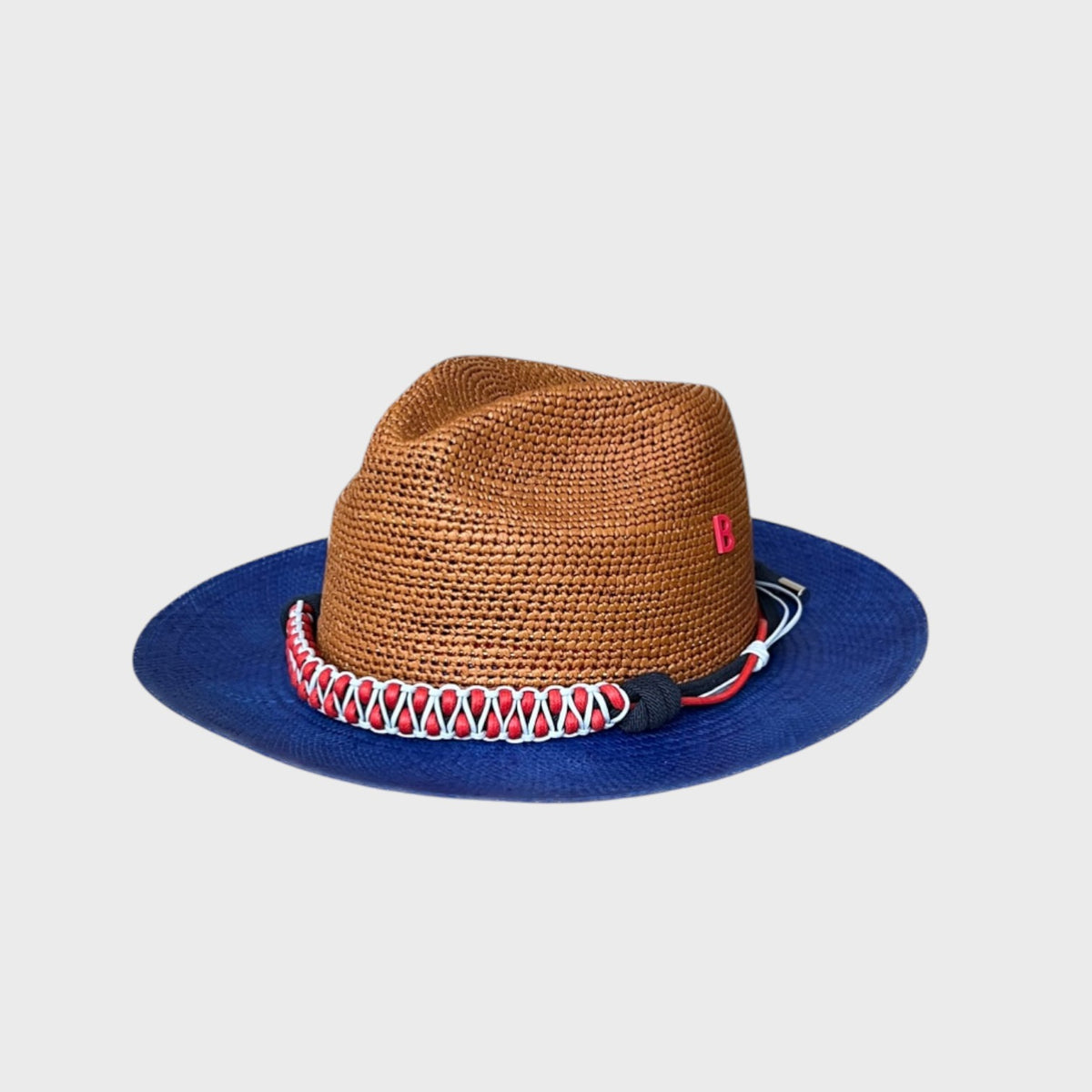 Brown raffia hat with blue rim and decorative macramé band on a light gray background
