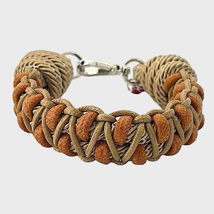 A braided macramé bracelet with shades of brown and light brown. It ends and a silver clasp, shown on a light gray background.