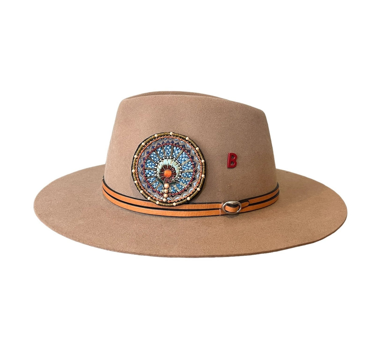 A brown wool hat with a hand embroidered brooch and a double leather accents and a letter 'B' on the brim.