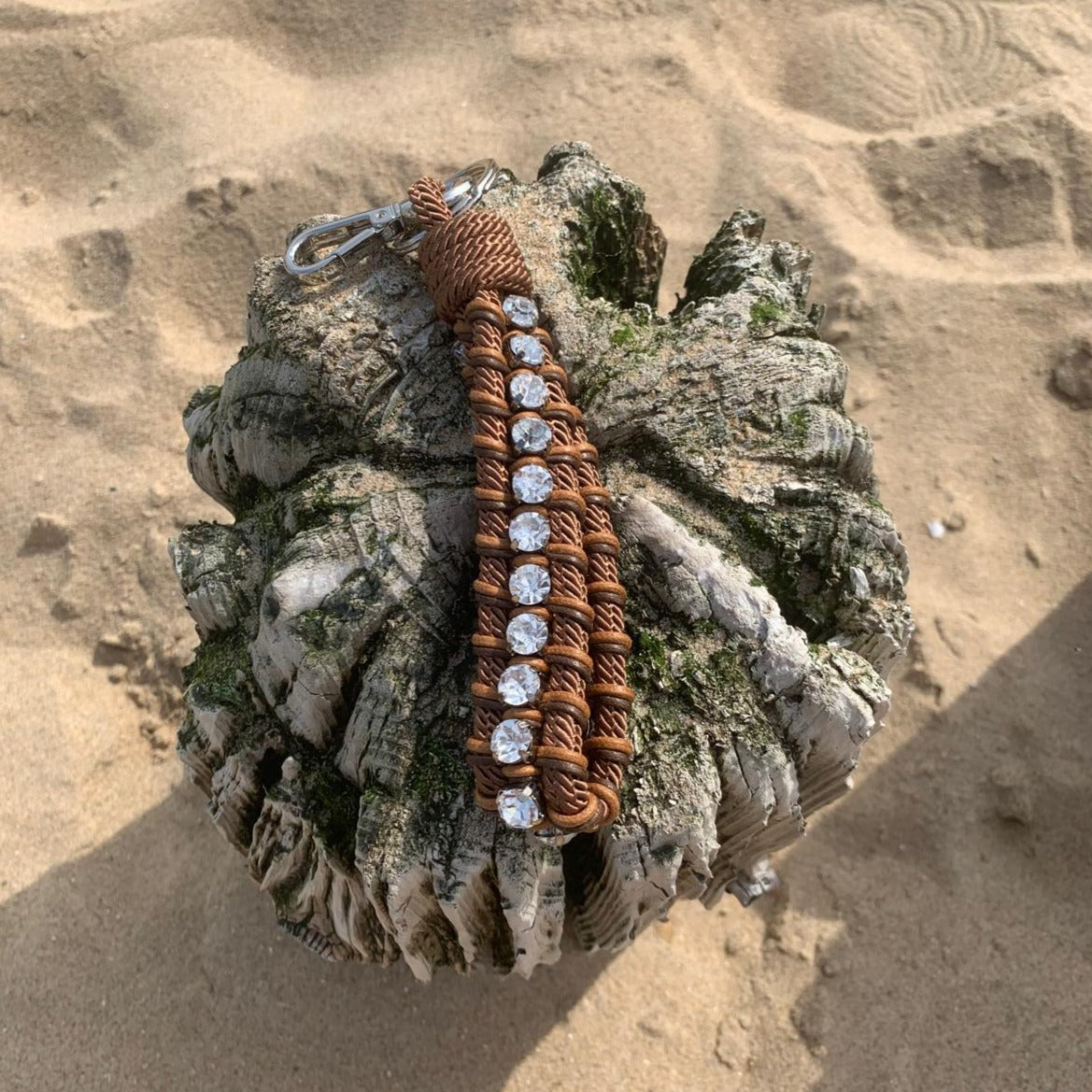 A brown macramé braided keychain with silver stones.