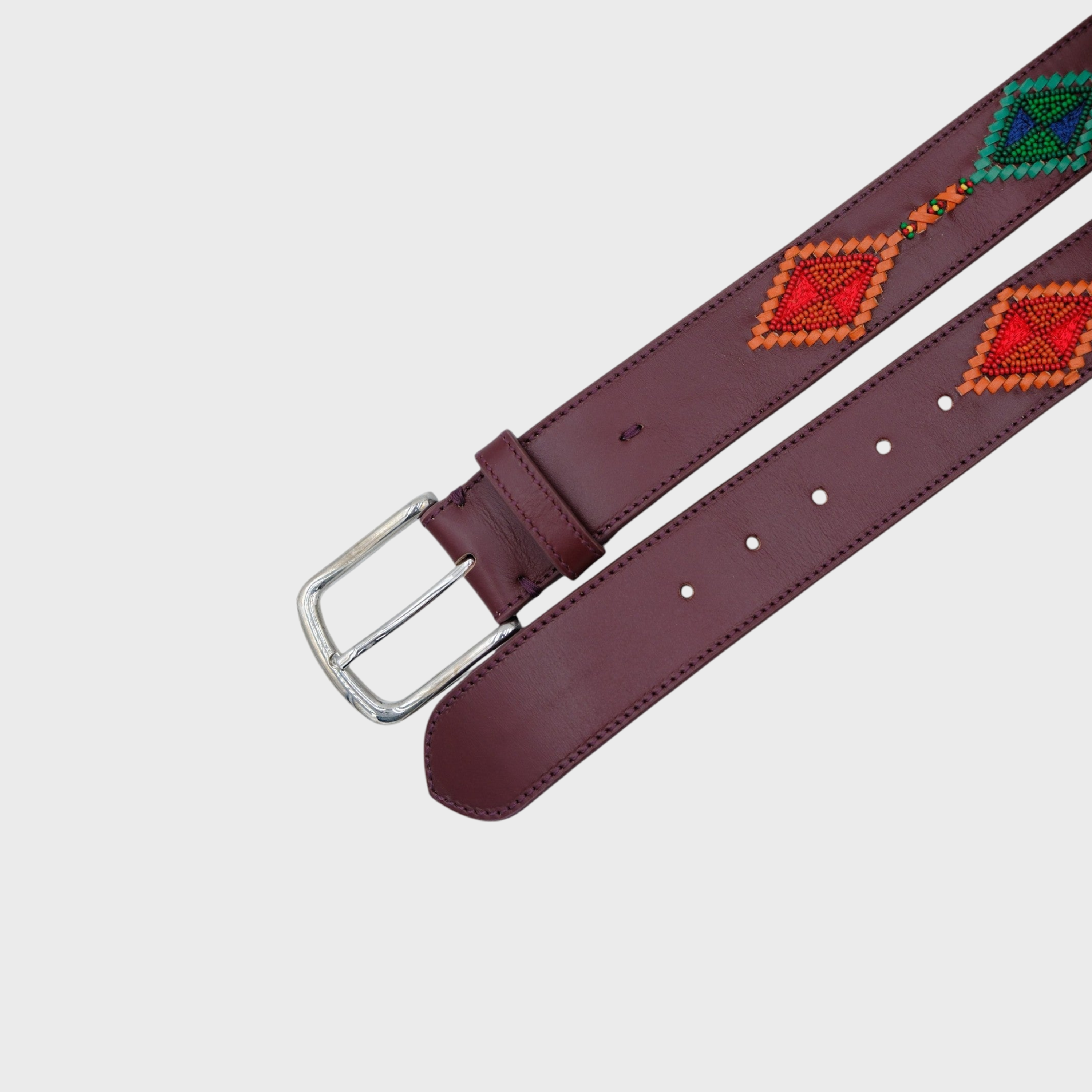 A burgundy leather belt with a silver buckle, featuring colorful geometric diamond patterns in red, orange, green, and blue along the strap, displayed on a light gray background.