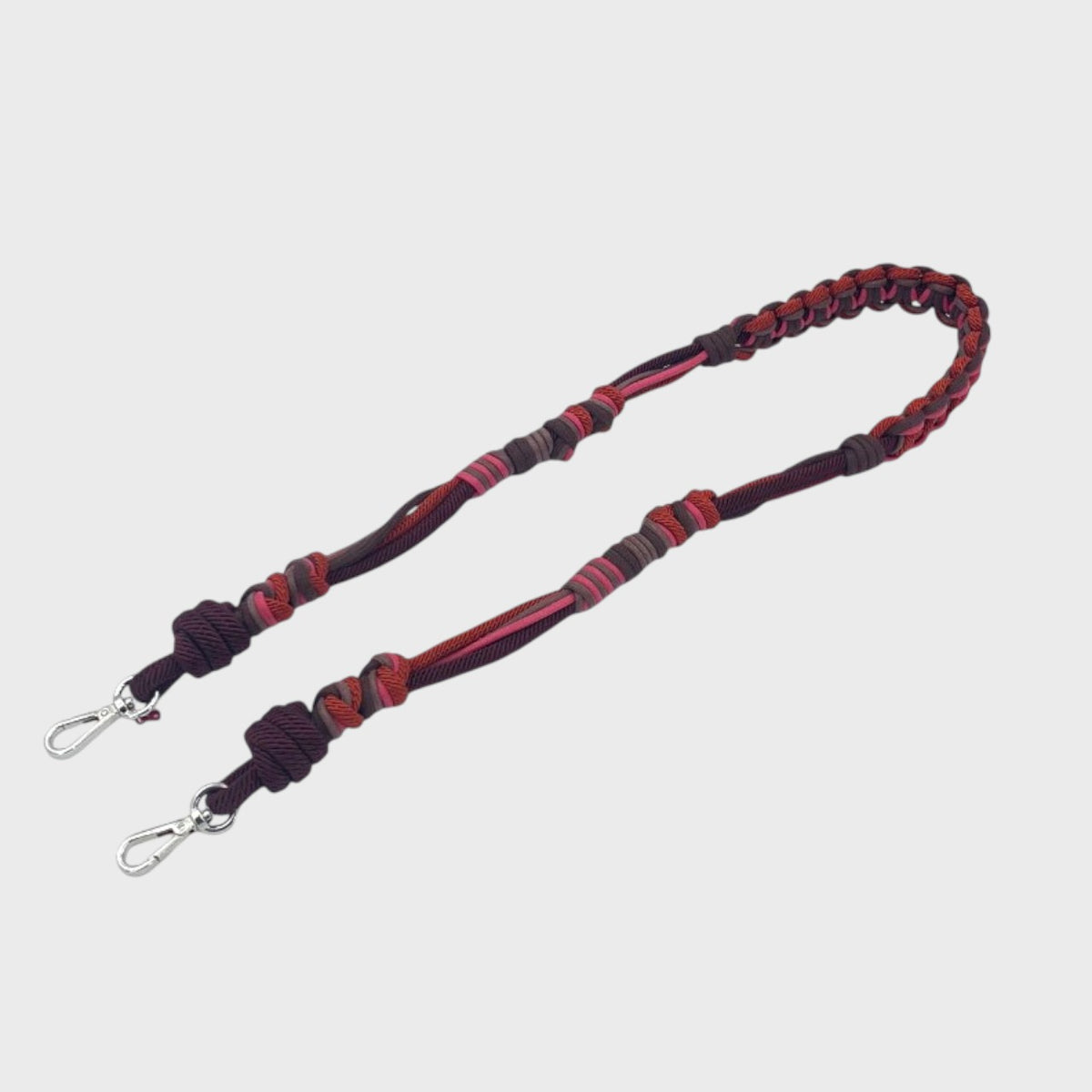 A long macramé bag strap with brown, pink and red patterns.