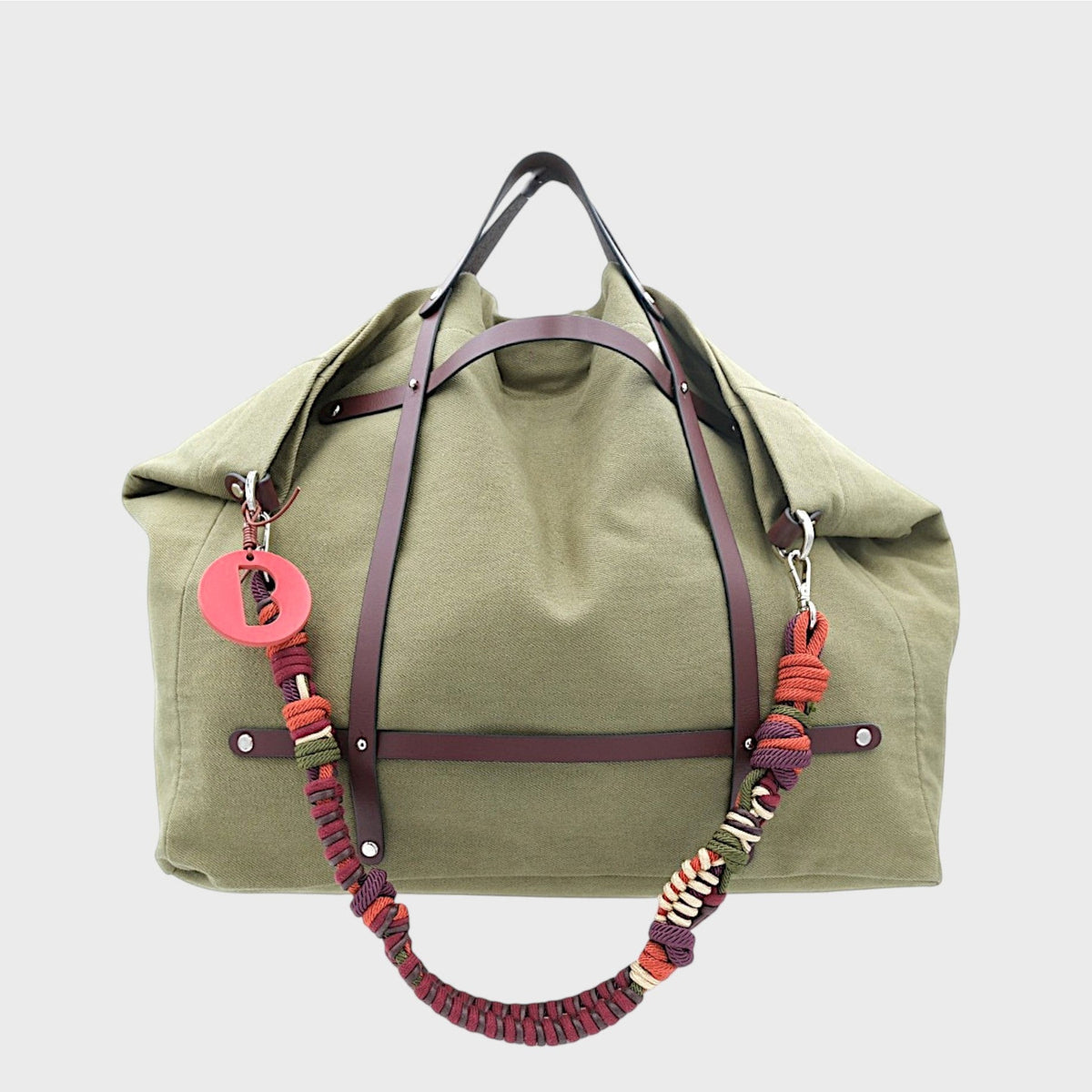 Green bag with a colorful macrame strap on a light gray background.