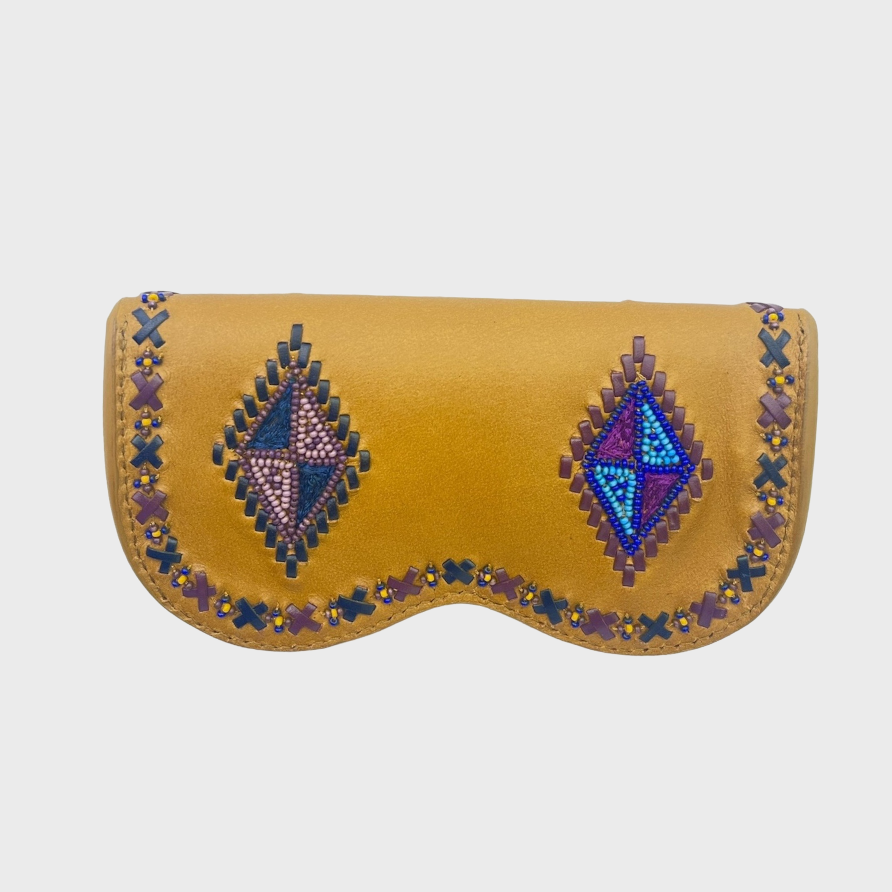 A mustard yellow leather eyeglasses case featuring two large embroidered geometric diamond patterns in purple, blue, and green, bordered by small stitched crosses, shown on a light gray background.
