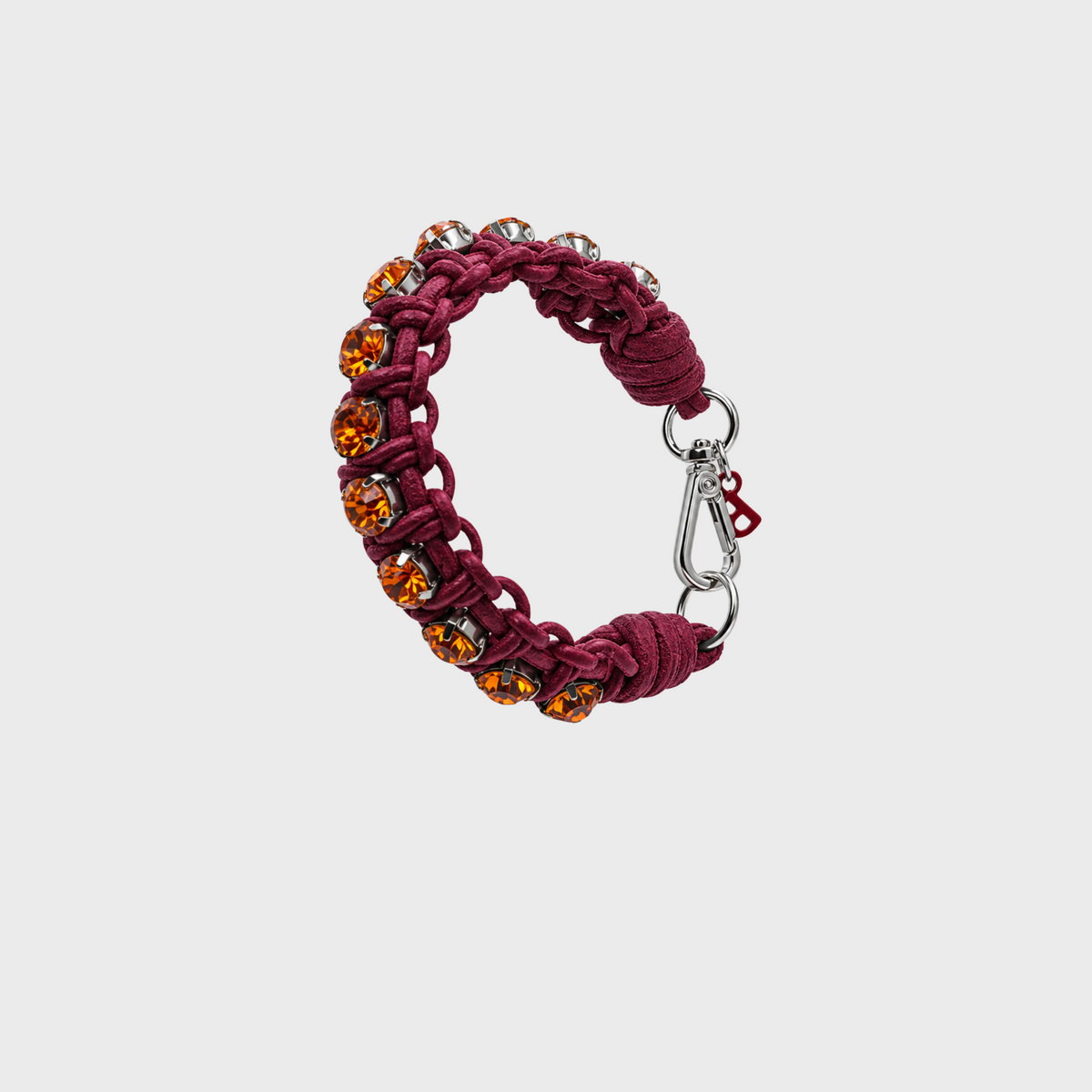 A burgundy macrame bracelet with amber-colored faceted crystal rhinestones and a silver clasp, shown on a light gray background.