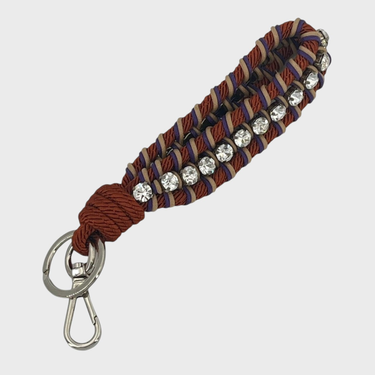 Keychain with copper, beige and purple patterned band and rhinestones on a white background