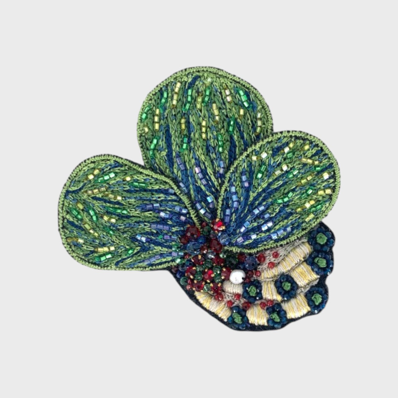 An embroidered brooch representing coral leaves with white, blue and green details.