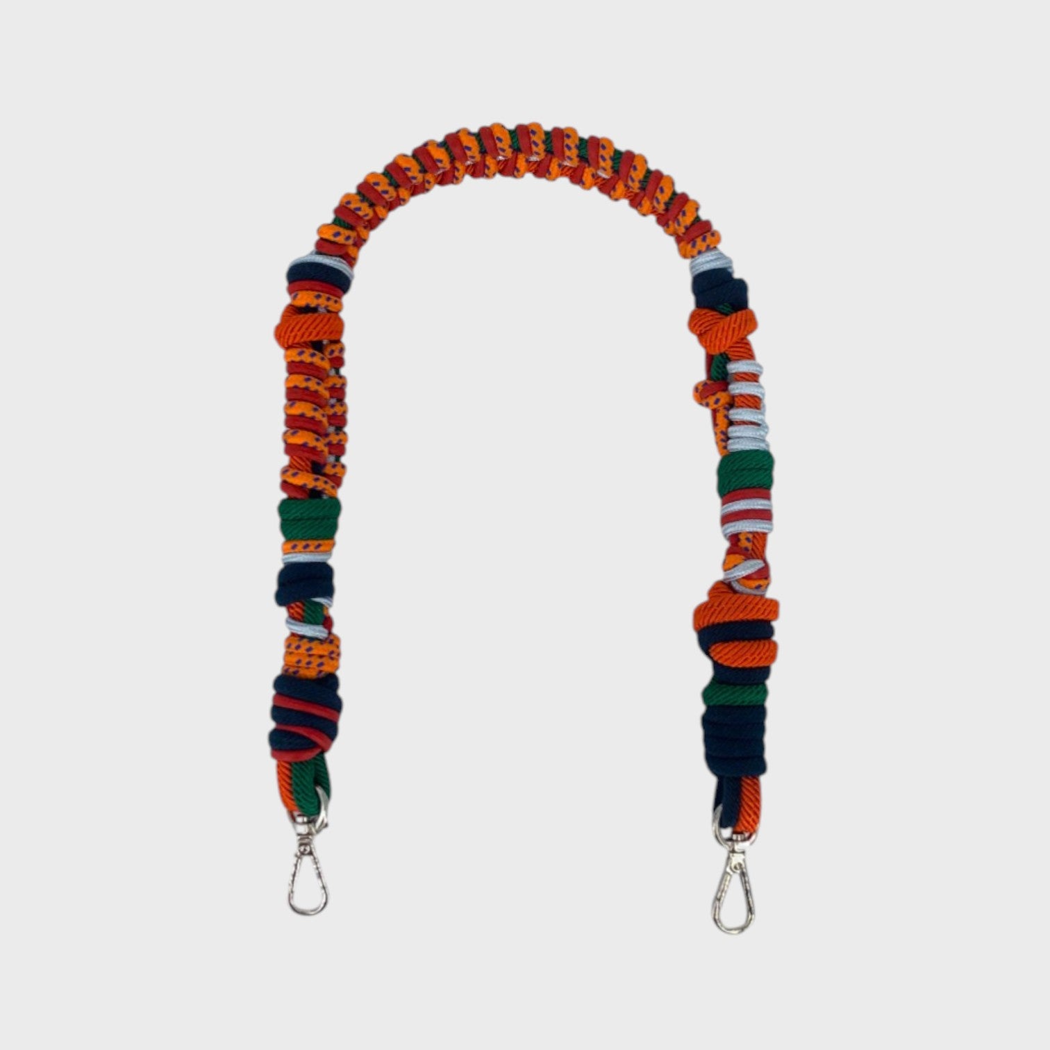 Multicolored braided macramé bag strap in bright and dark orange, dark green, and white, shown on a light gray background.
