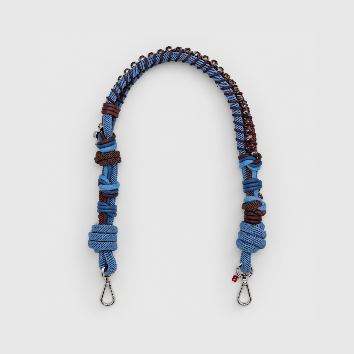 Multicolored braided macramé bag strap in blue and chocolate, featuring some purplee colored beads and shown on a light grey background.