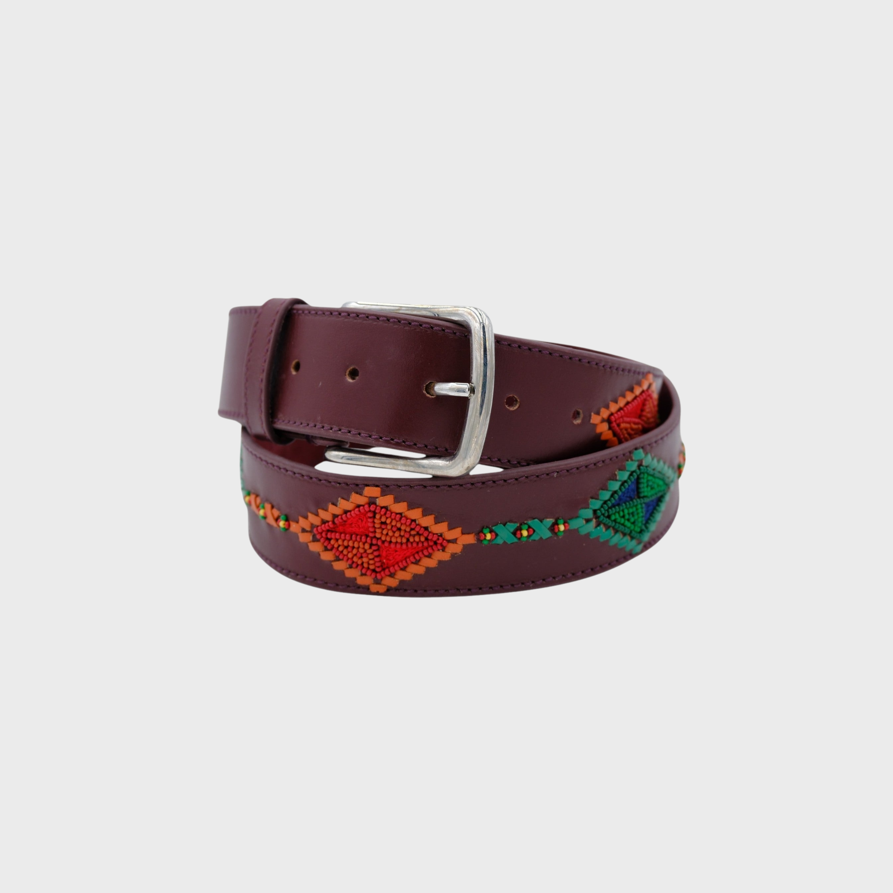 A burgundy leather belt with a silver buckle, featuring colorful geometric beadwork in red, orange, green, and blue along the strap, coiled on a light gray background.