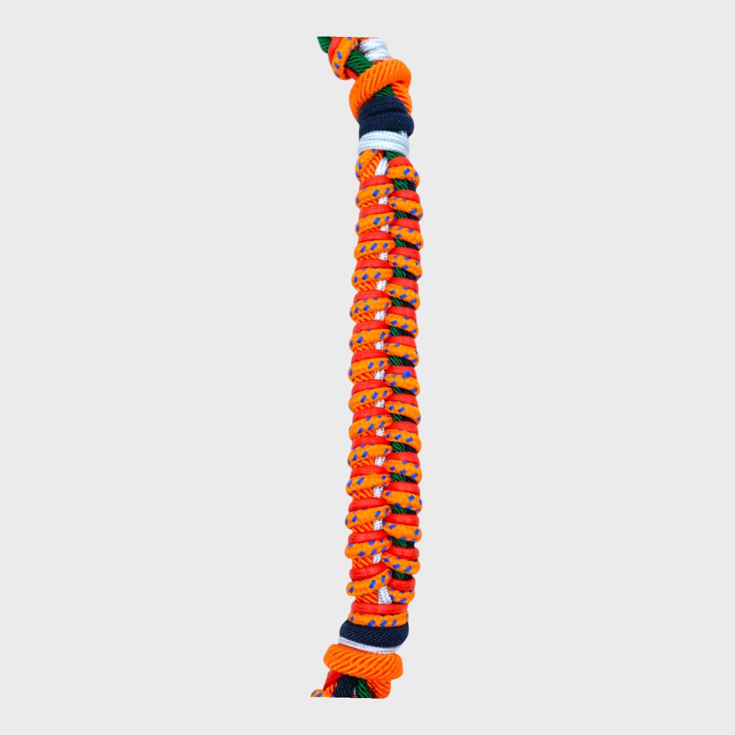Close up of the multicolored braided macramé bag strap in bright and dark orange, dark green, and white, shown on a light gray background.