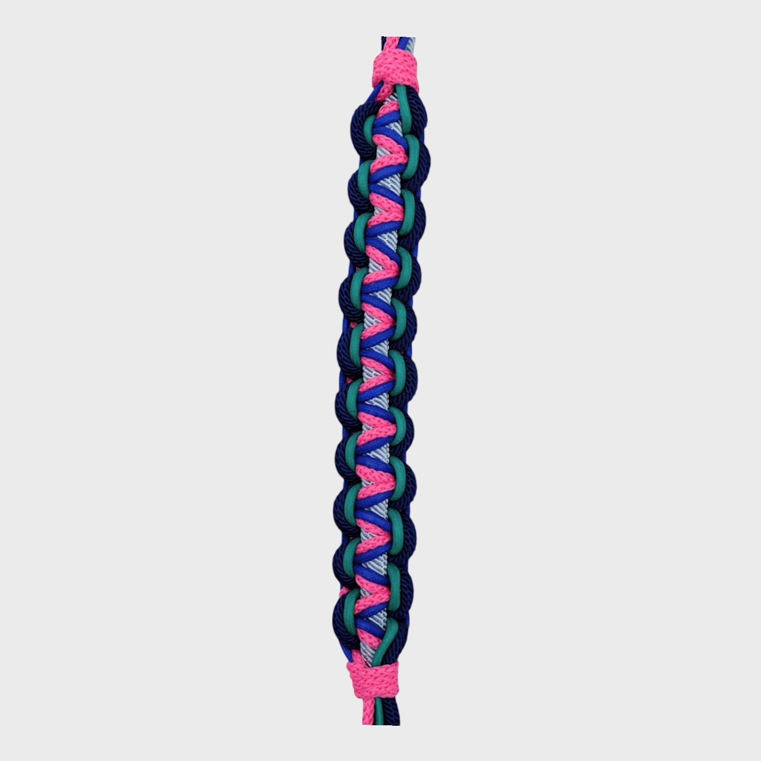 Close up showing the detail of the multicolored braided macramé bag strap in bright pink, bright blue, and light blue with metal hooks on a light gray background.