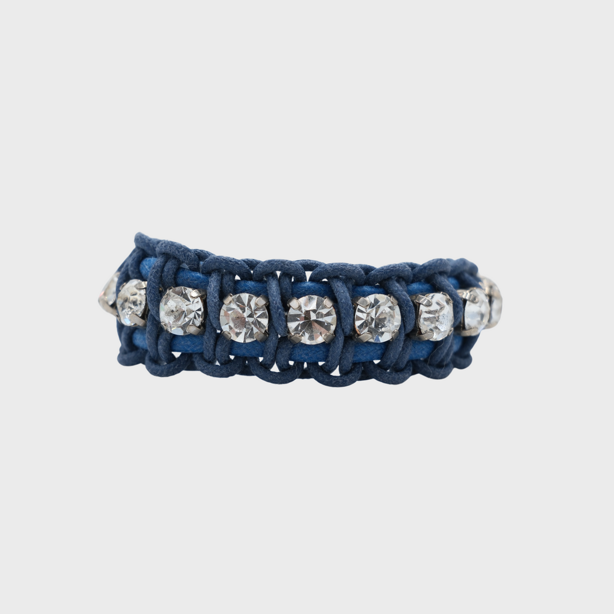Close-up of the Juliette bracelet showing a blue woven macrame and clear white beads all around on a light grey background.