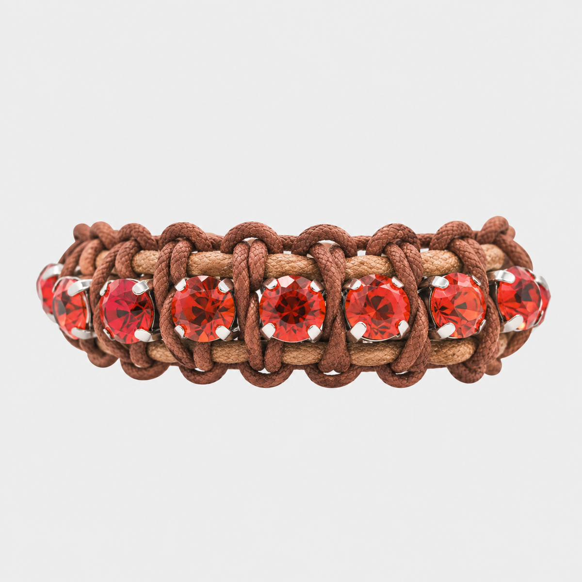 A braided cord macrame bracelet featuring alternating brown and tan woven cords with a row of faceted red gemstones in silver bezel settings, shown against a light gray background.