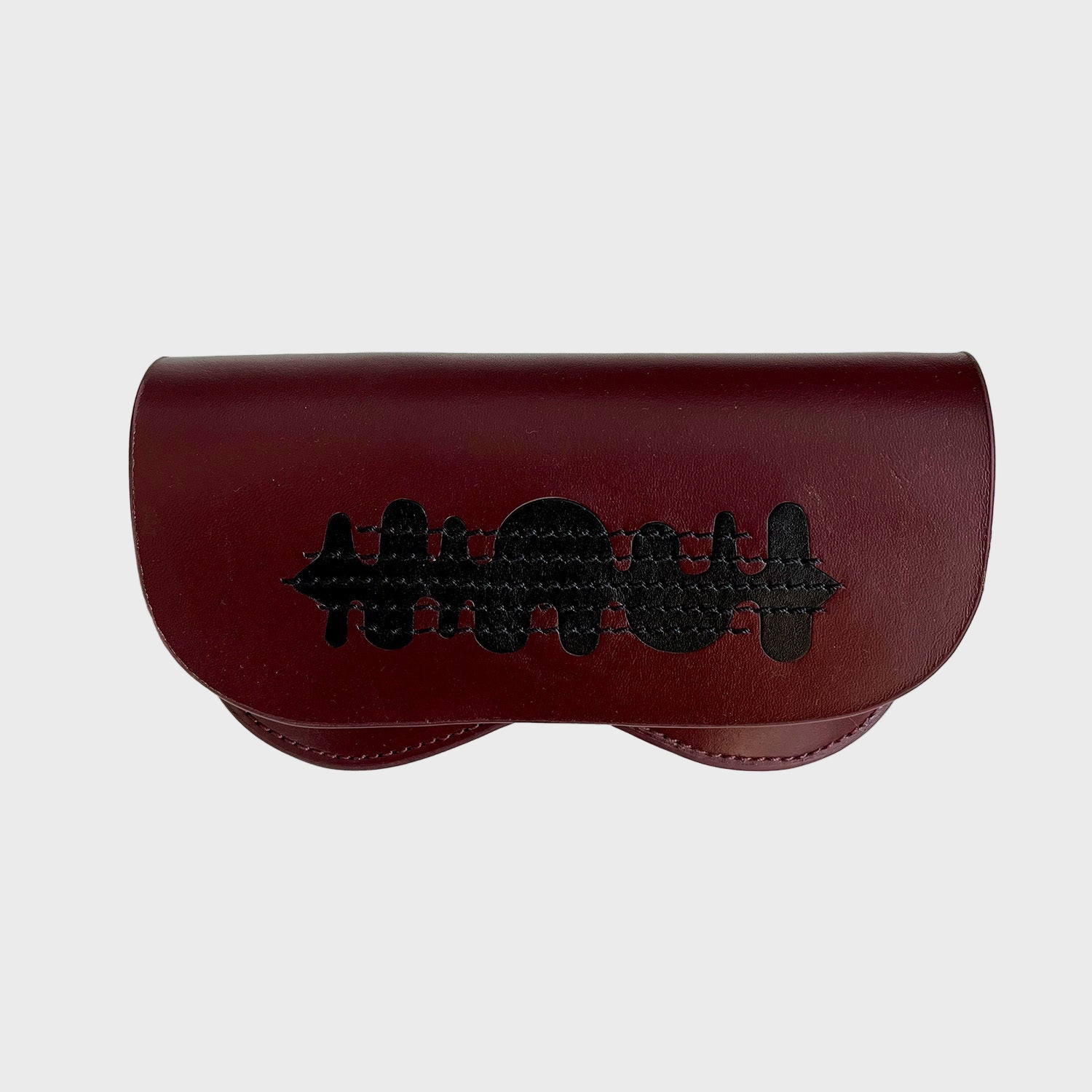 A glasses case burgundy with black embroidered details on it.