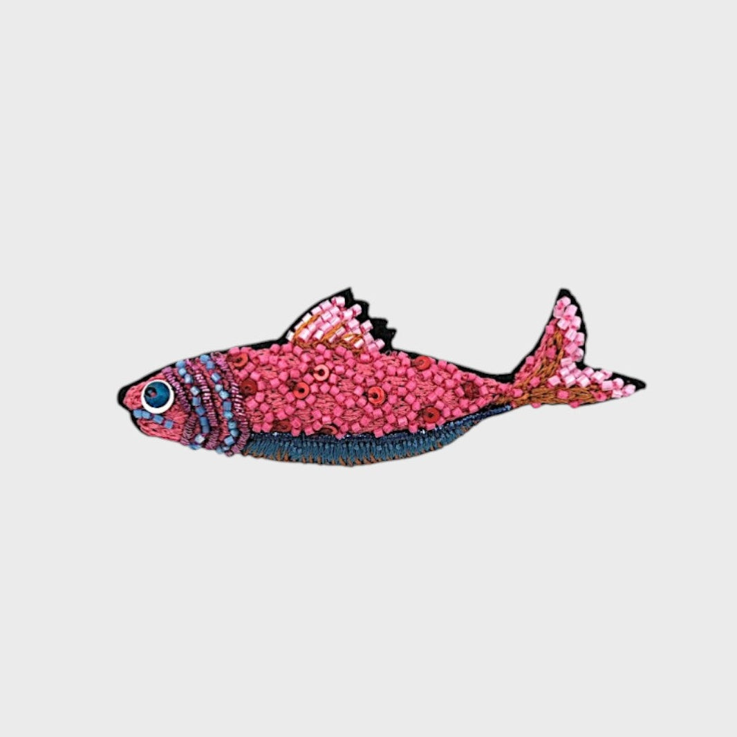 A embroidered pink fish with blue details.