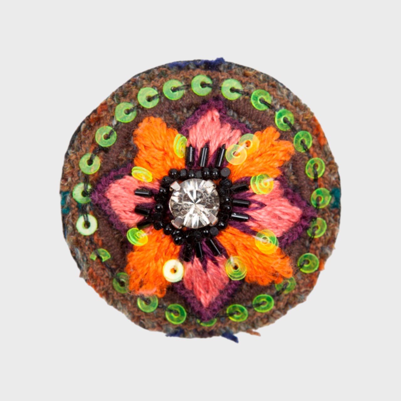 An embroidered brooch representing a flower with orange and pink petals.