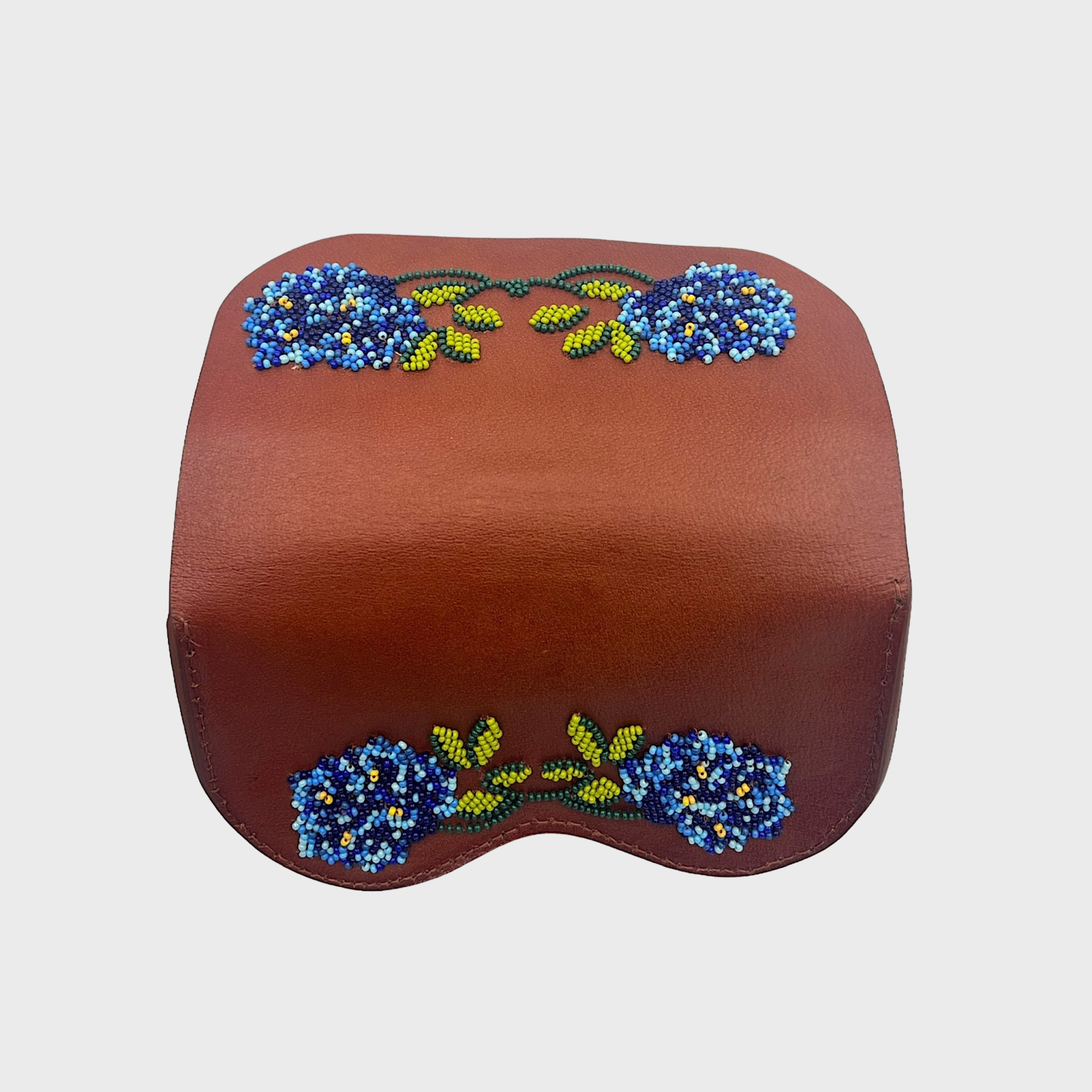 The back of a brown leather glasses case with blue and green beaded floral embroidery on the top and bottom, shown against a light gray background.