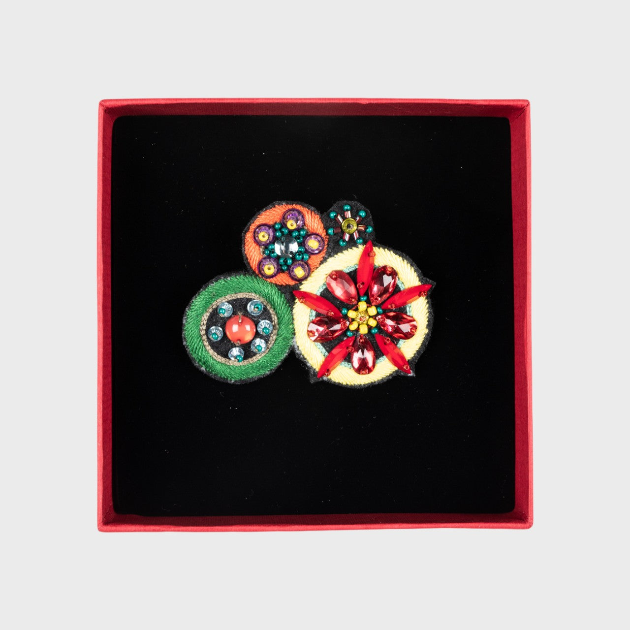 An embroidered brooch with four flowers in a box.