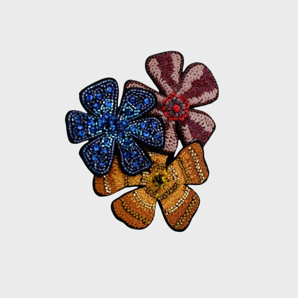 An embroidered flower brooch, with red, yellow and blue flowers.