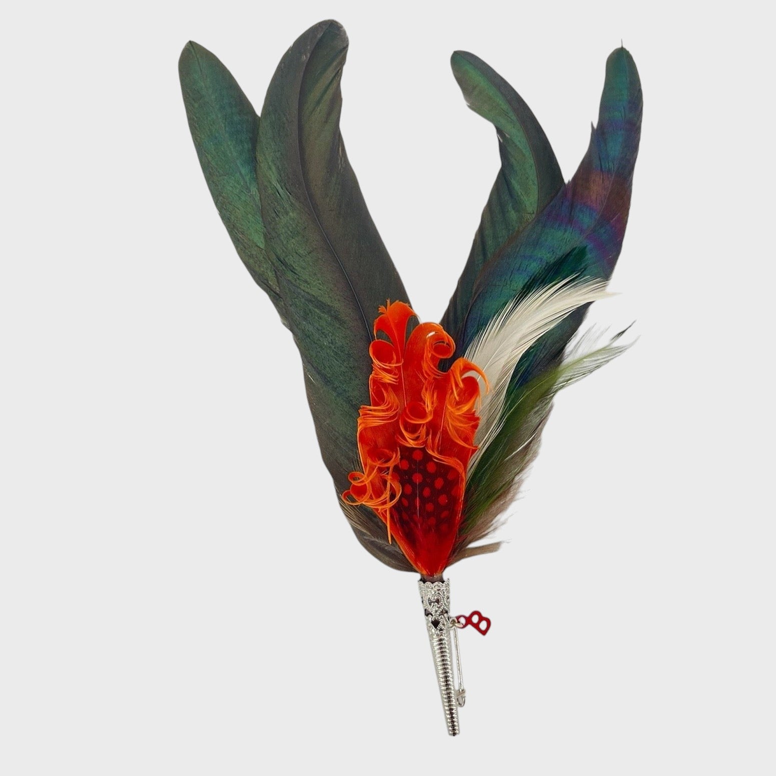 Large green and red-orange feathered brooch on a light gray background