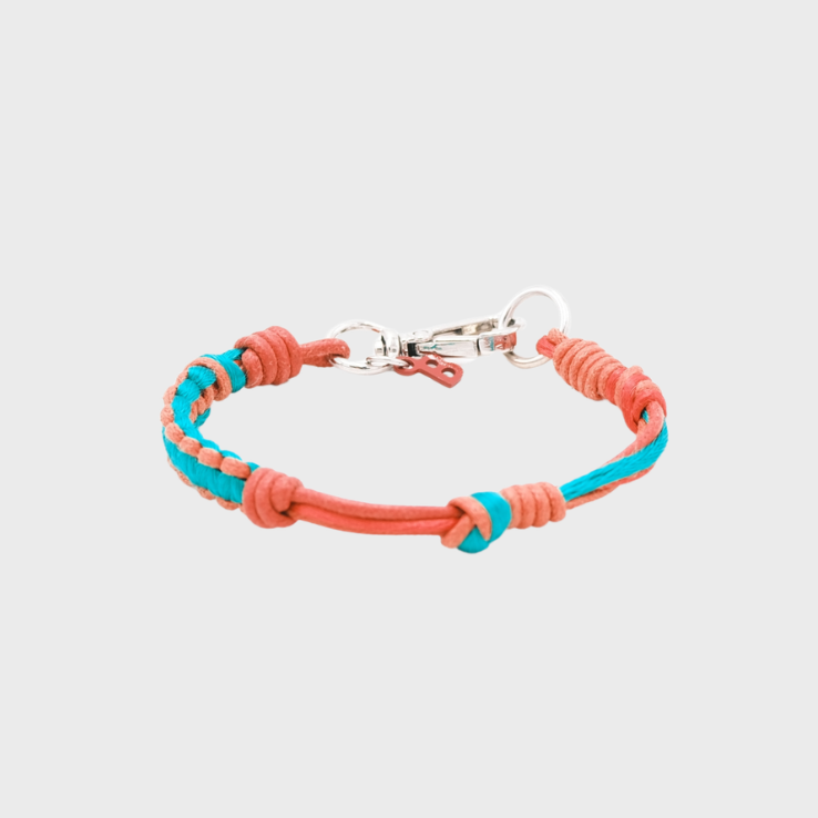 A thin braided bracelet with red and green macramé, featuring a silver metal clasp.
