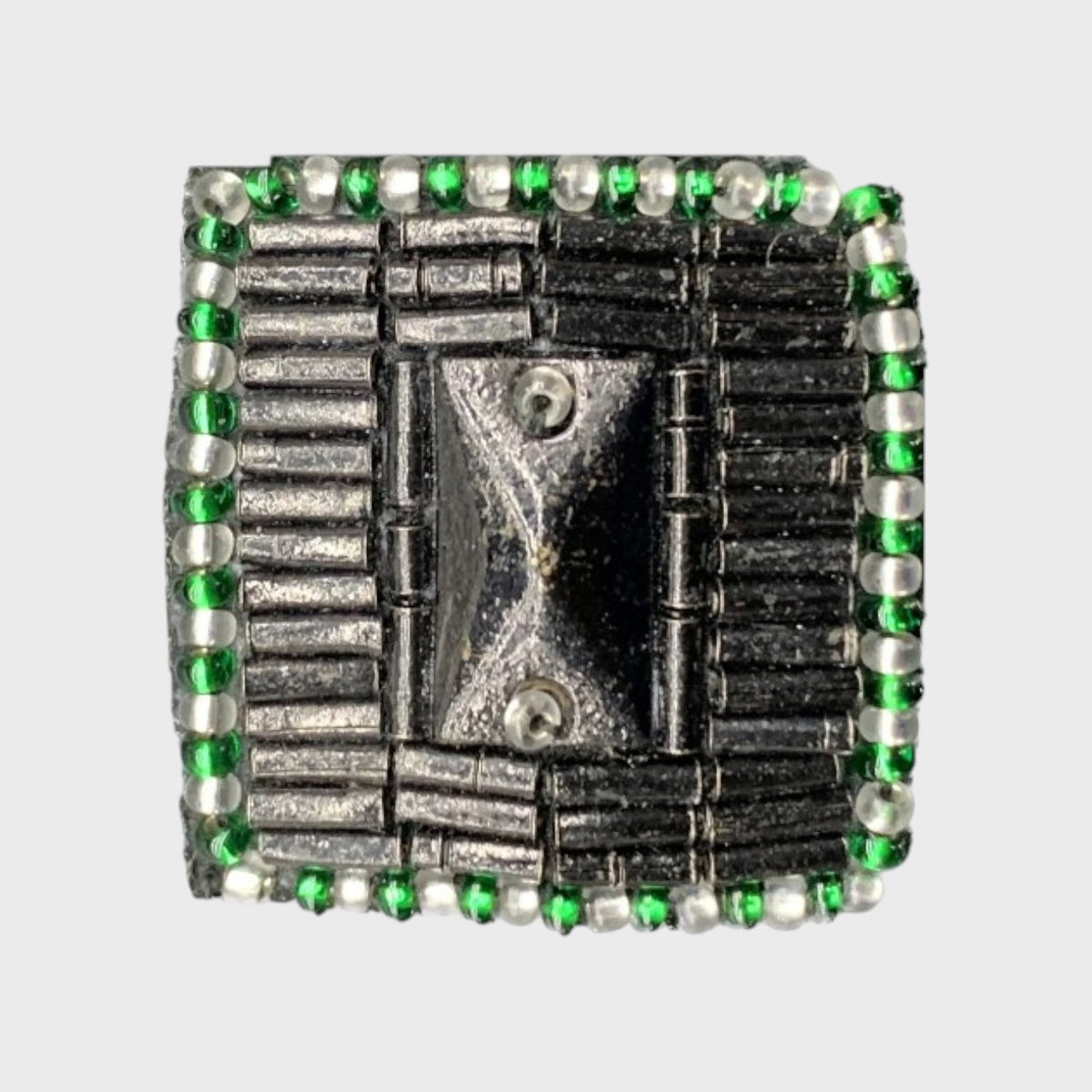 An embroidered brooch with silver and green details and pearls, representing a button.