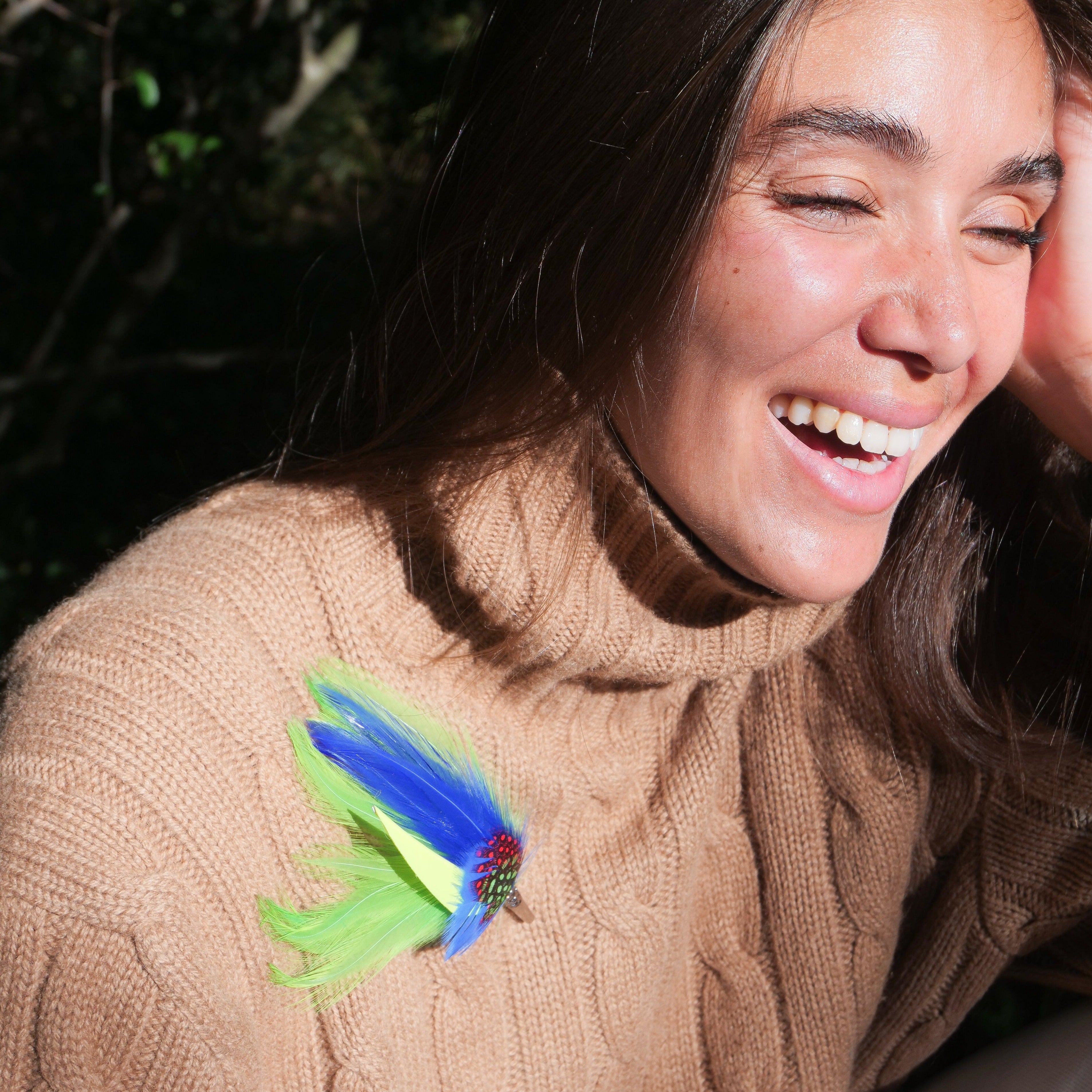 A model wearing the Elijah green and blue feather brooch.