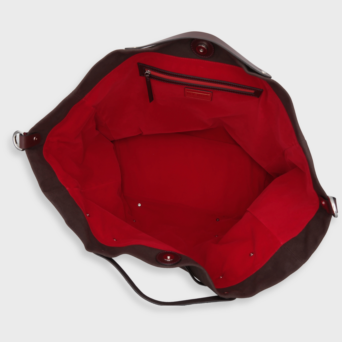 Top-down view of a dark brown handbag with a vibrant red interior lining, showing a zippered pocket inside.
