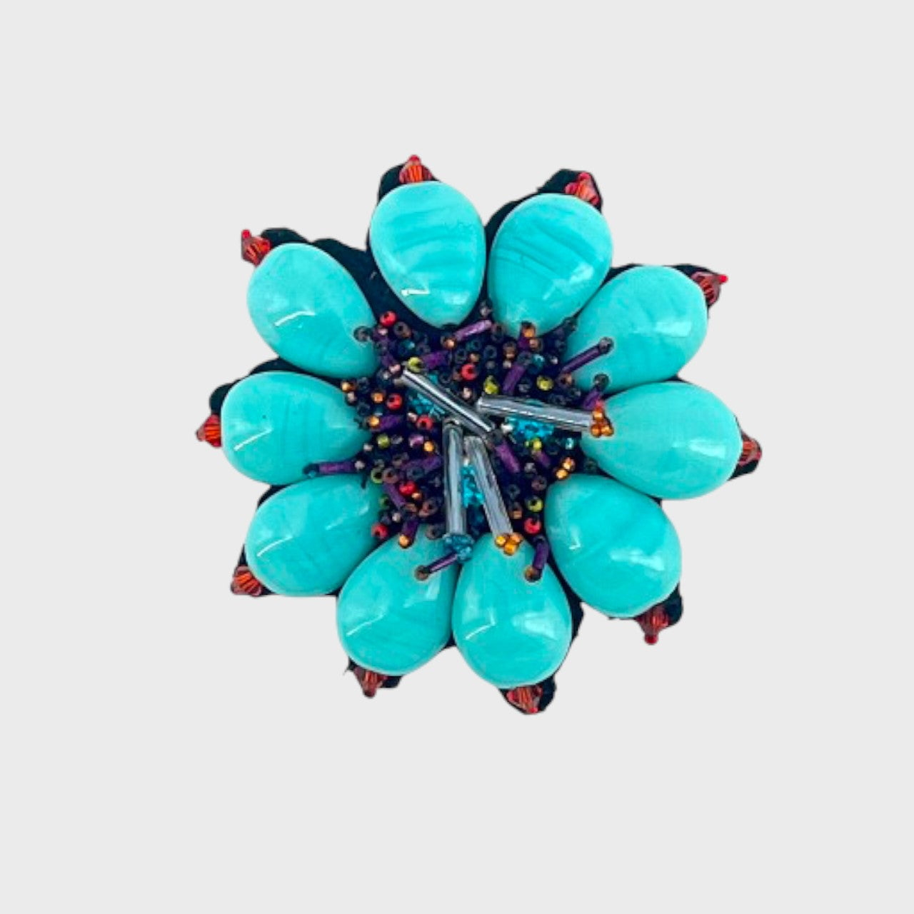 An embroidered brooch representing a blue flower with purple and red details.
