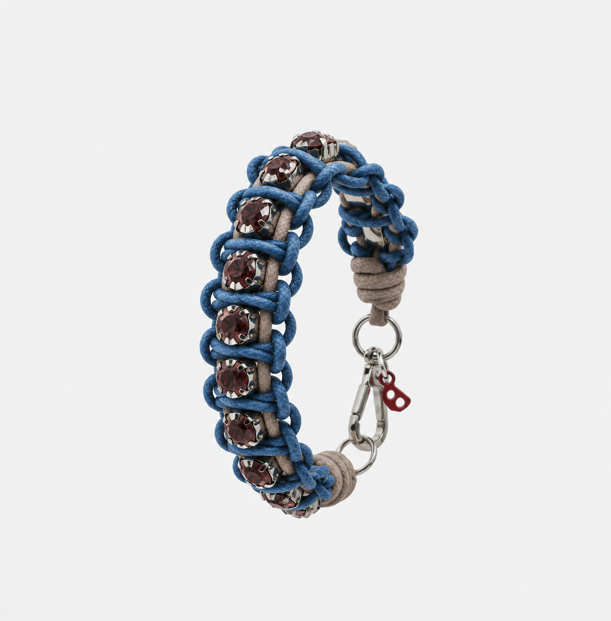 A handmade macrame bracelet featuring blue braided cords, brown leather loops, and faceted dark brown gemstones, finished with a silver clasp on a light gray background.